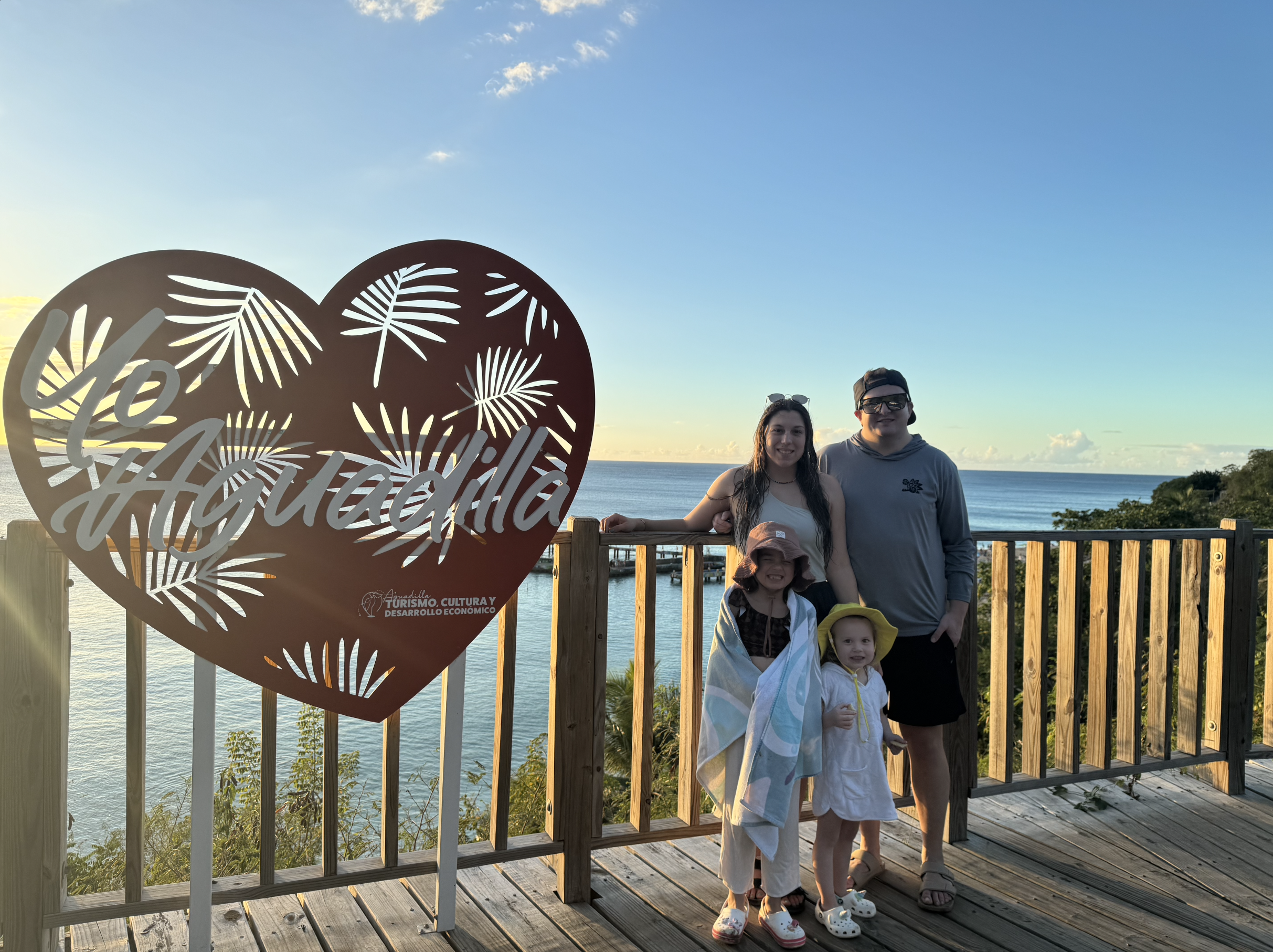 Travel Advisor Arliss, her husband, and two small daughters in front of a large beach at sunset