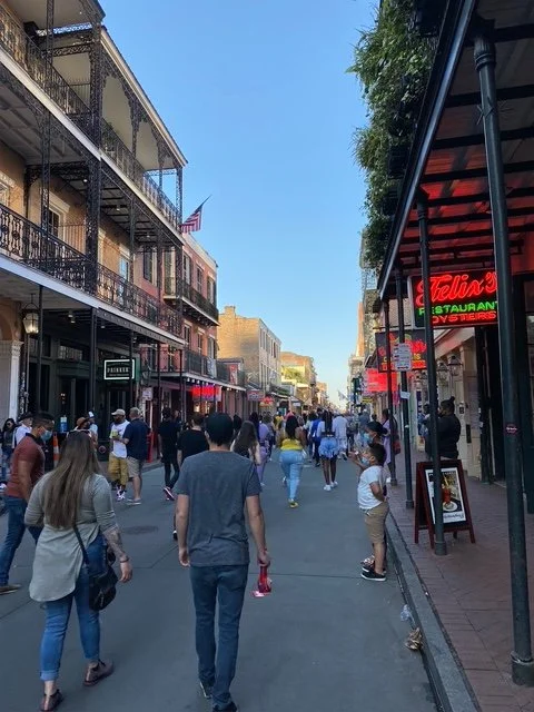 A quiet daytime view of Bourbon Street, lined with iron balconies and restaurant signage.