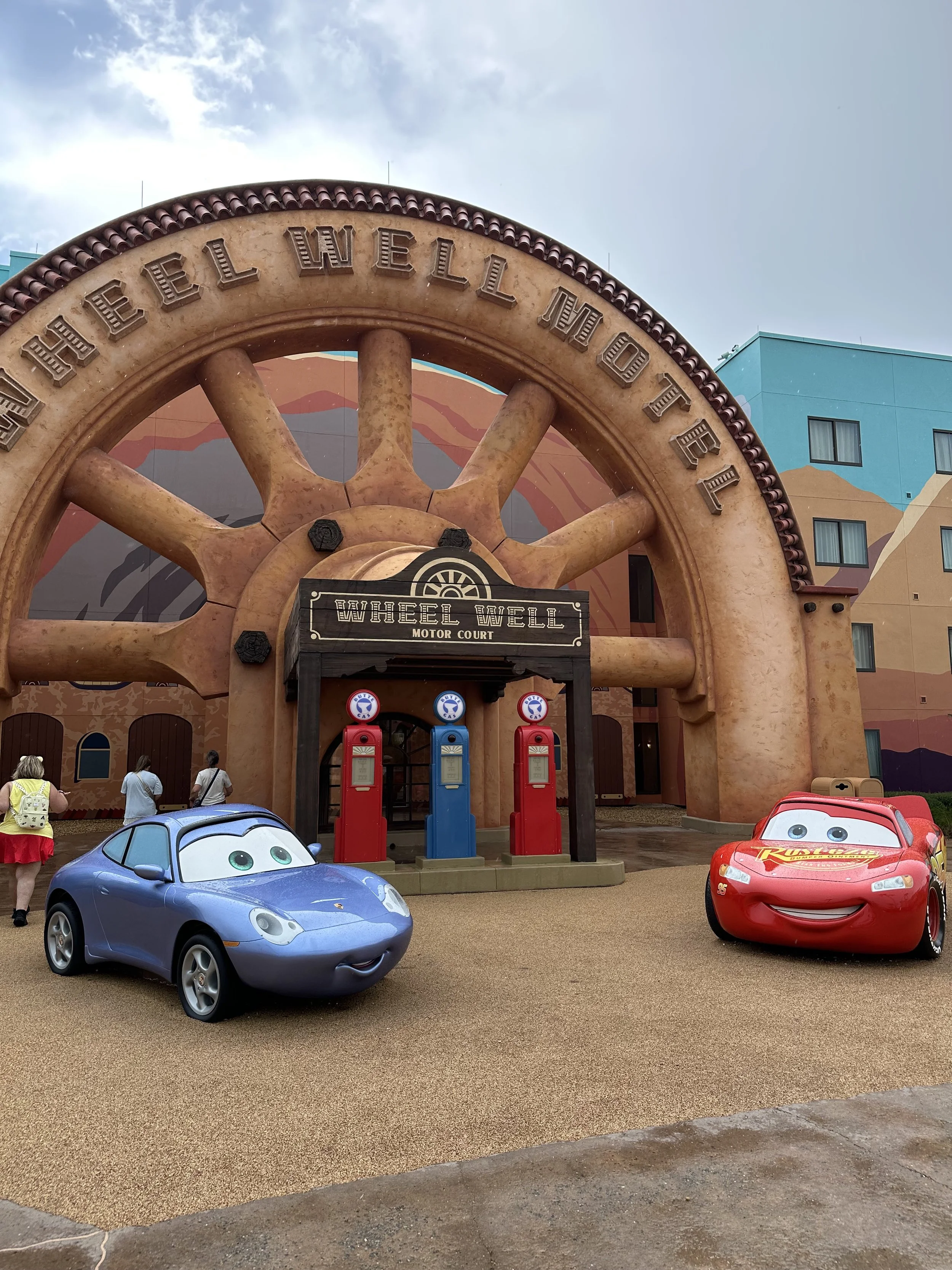 a red and blue car outside of a hotel behind it