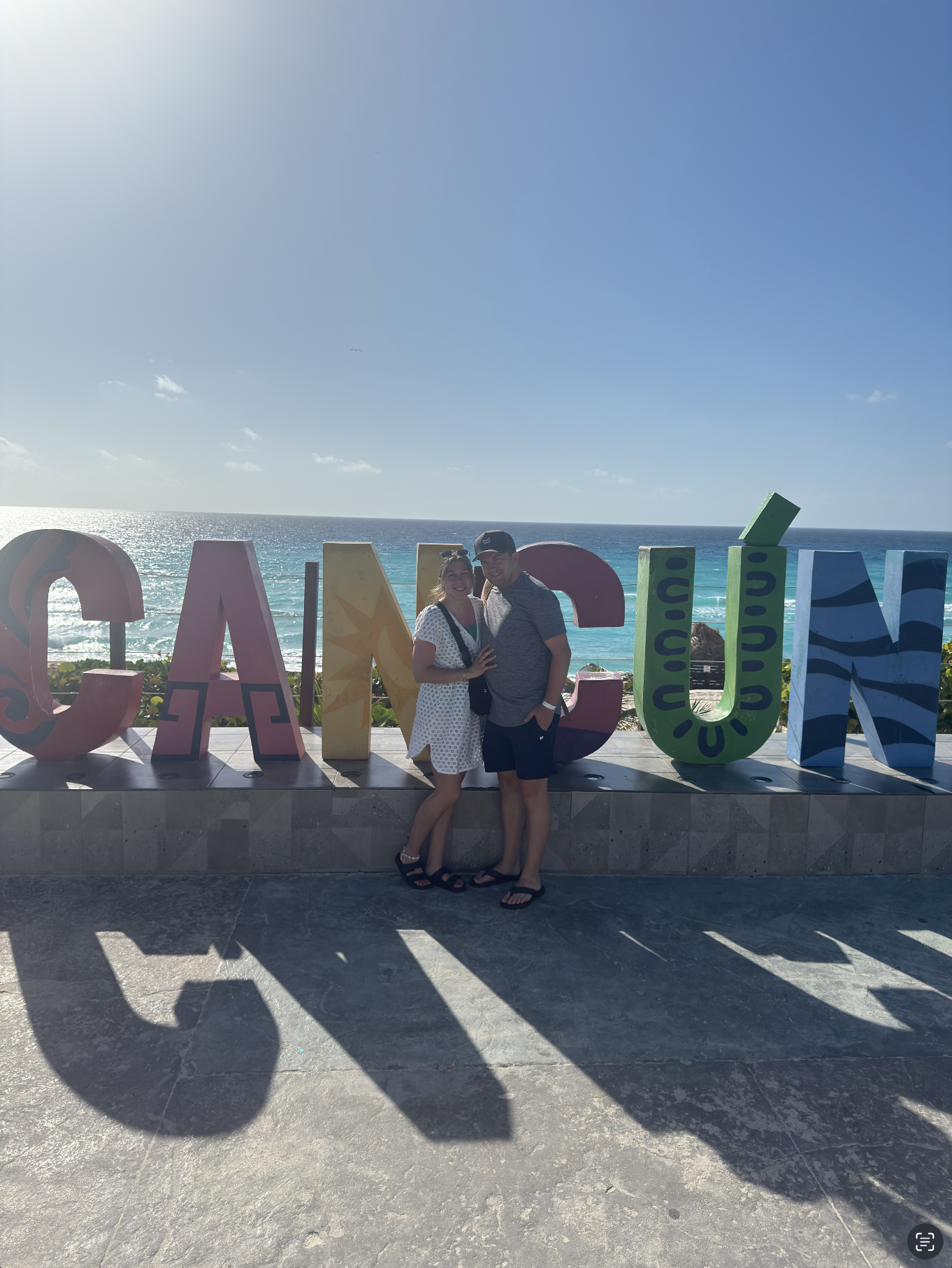 Travel Advisor Arliss and her husband in front of a cancun sign