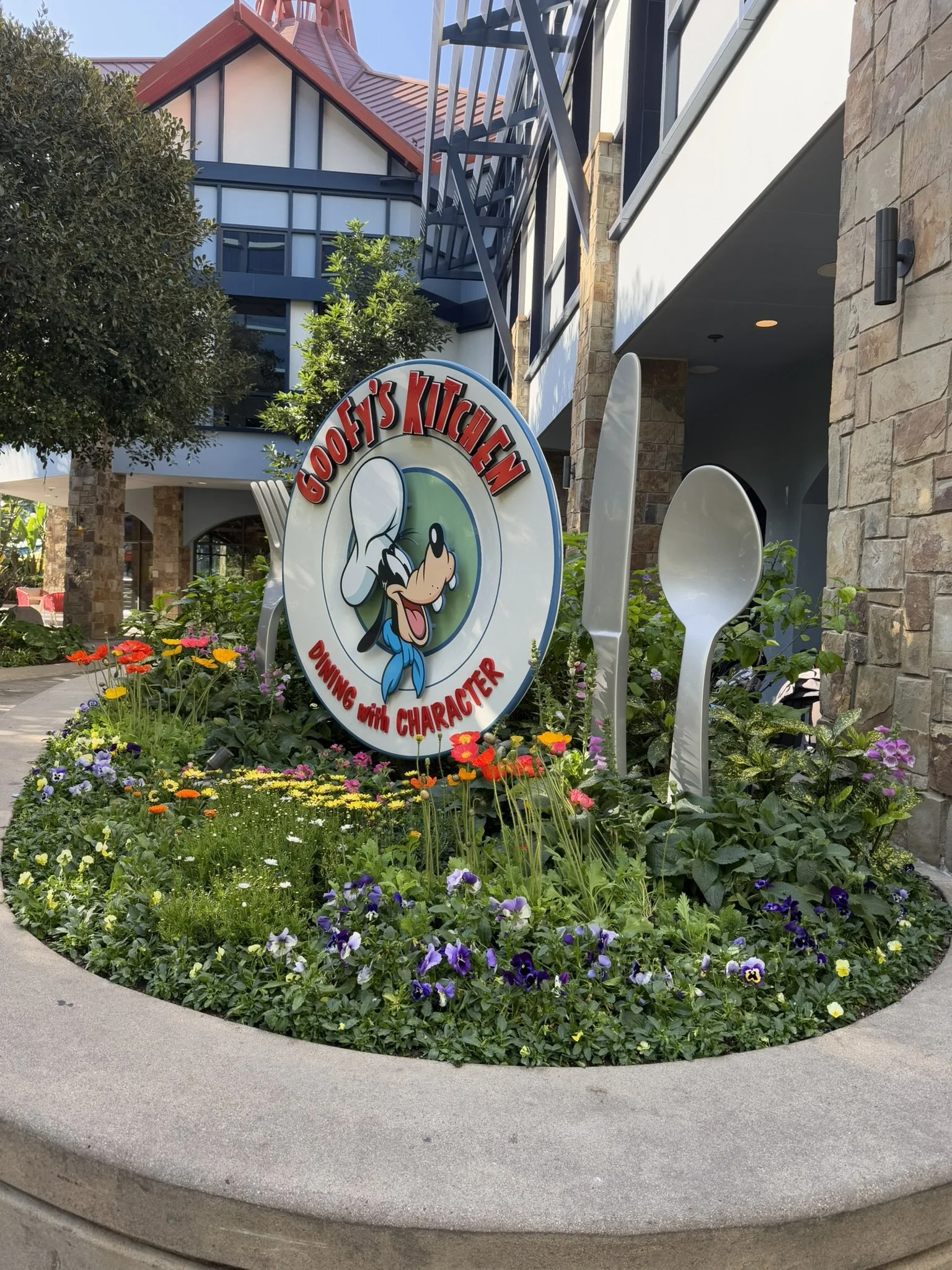 goofy's kitchen character dining sign in a flower bed at