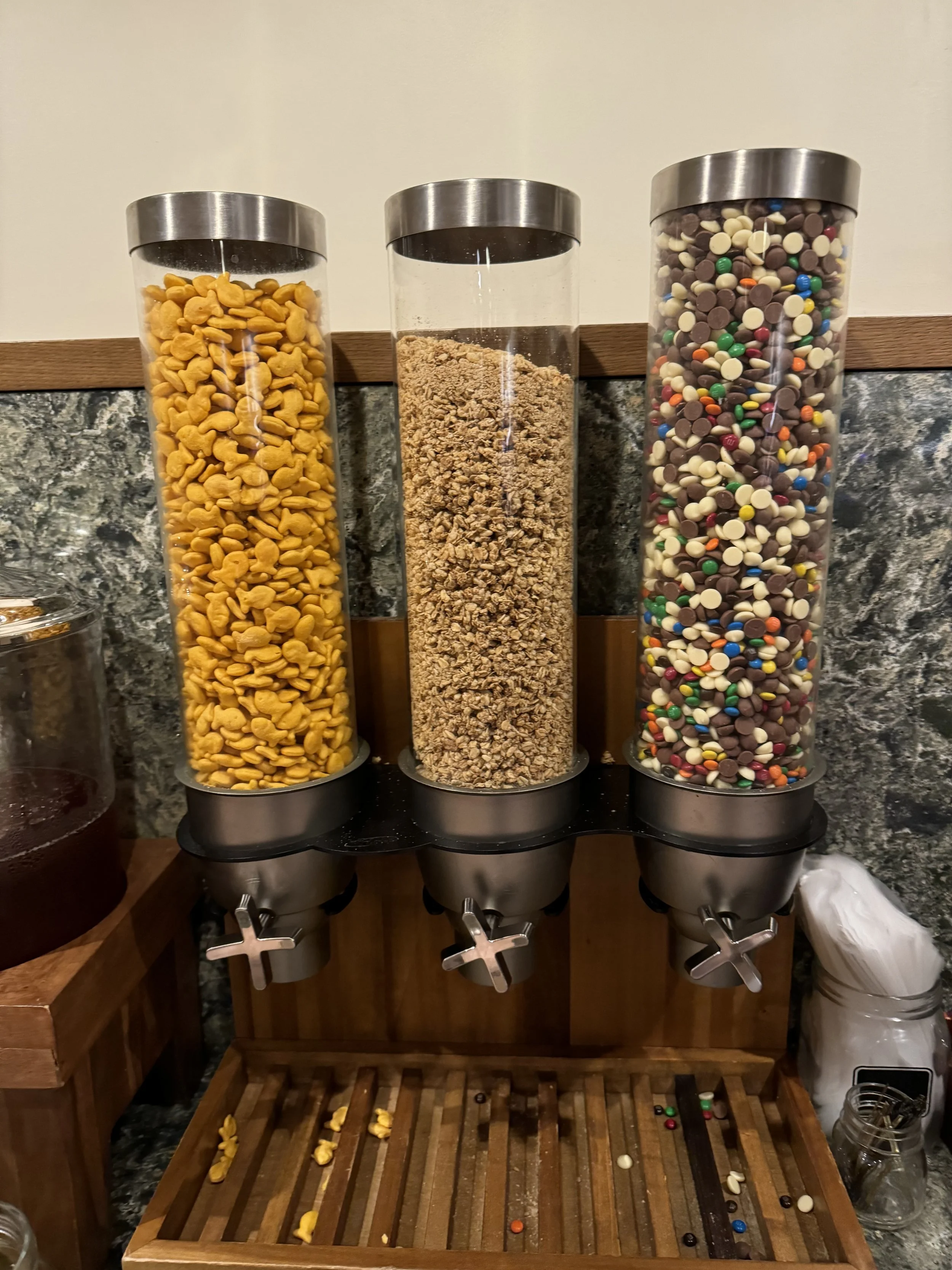 Snack dispensers stocked with goldfish crackers, granola, and chocolate candy in a Disney Club Level lounge.