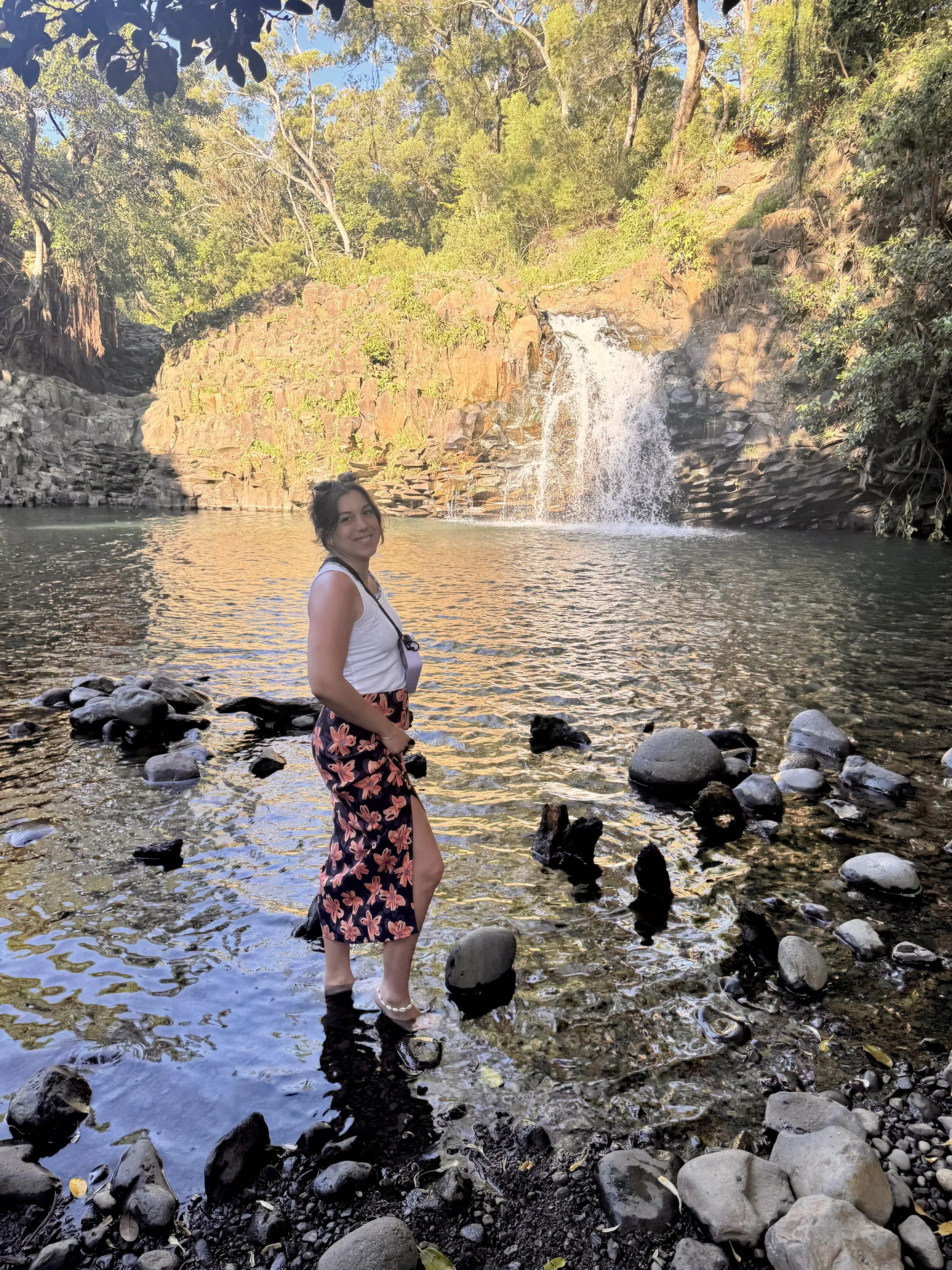 a woman standing sideways infront of a waterfall