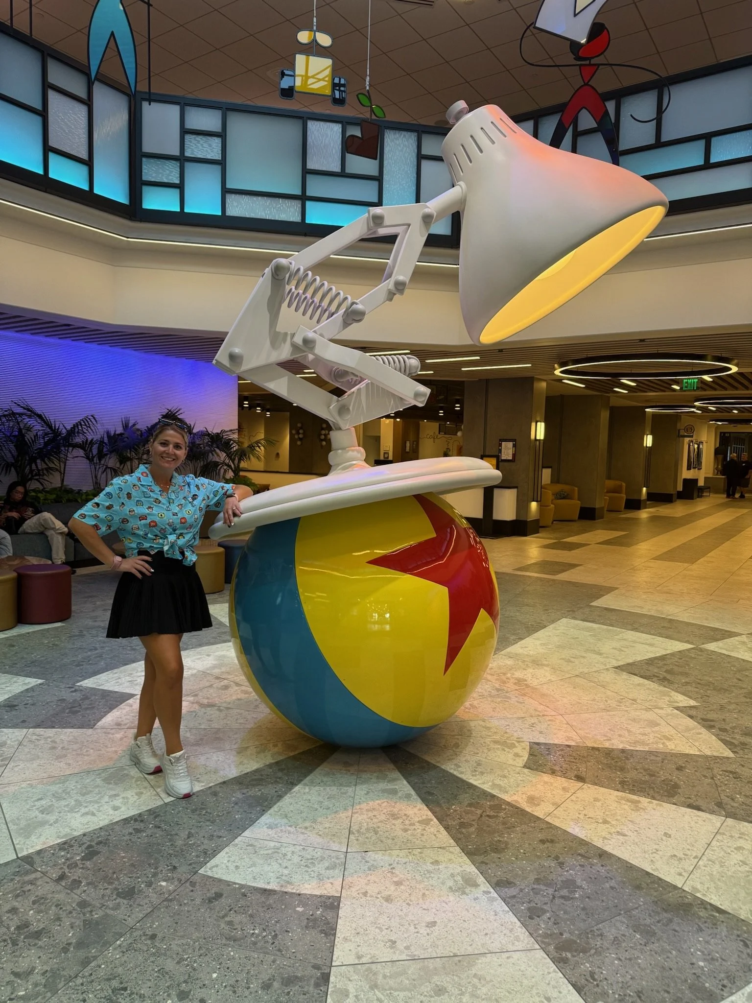 a woman smiling with her arm sitting on a yellow and blue ball with a life size lamp on top