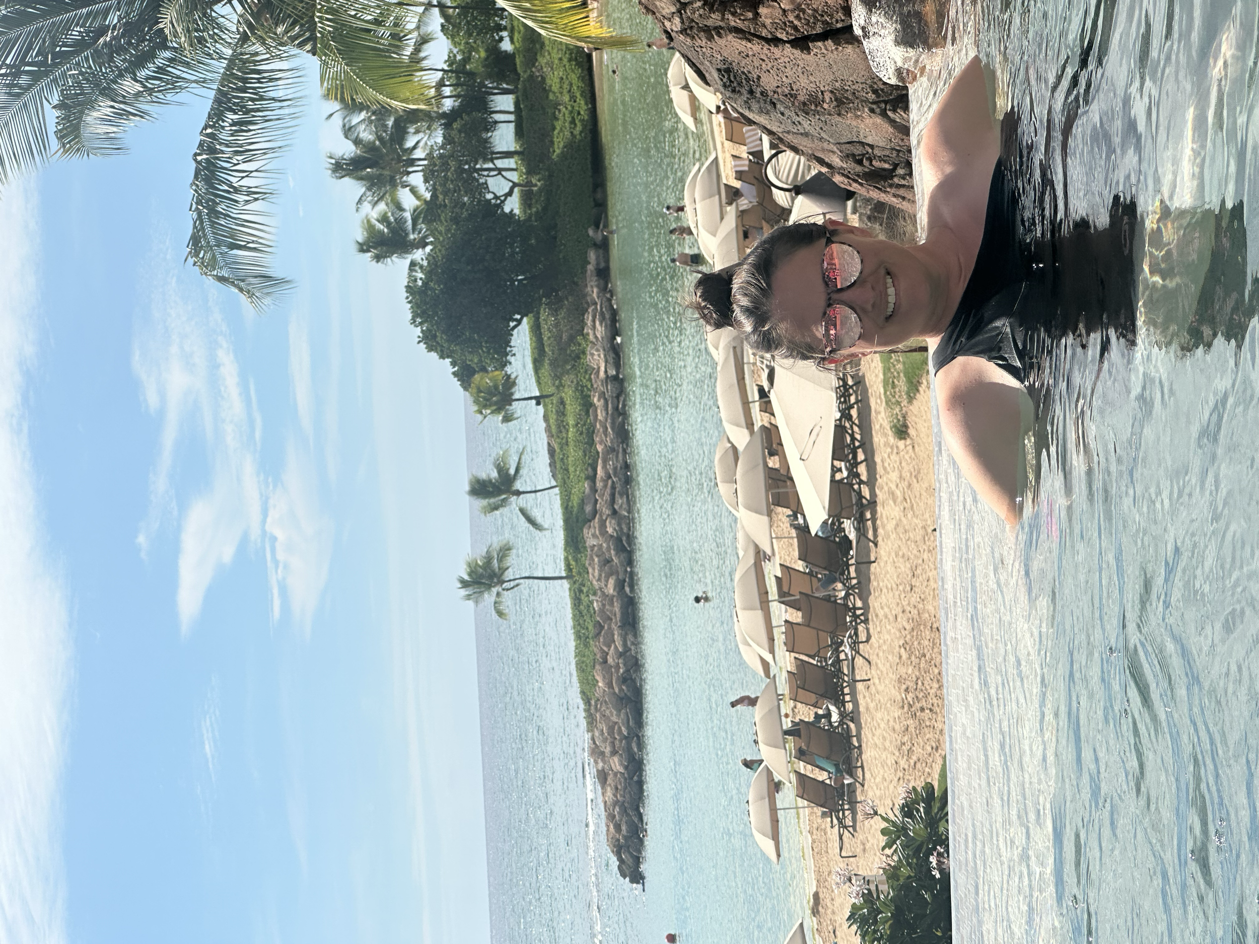 a woman sitting in a pool with the beach behind her