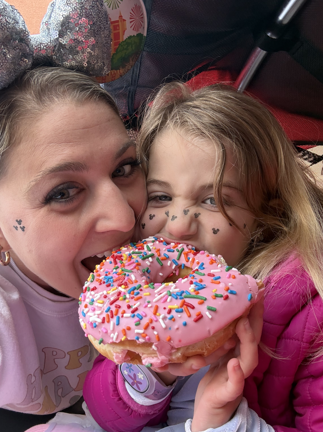 travel advisor lauren with her daughter eating a giant pink donut