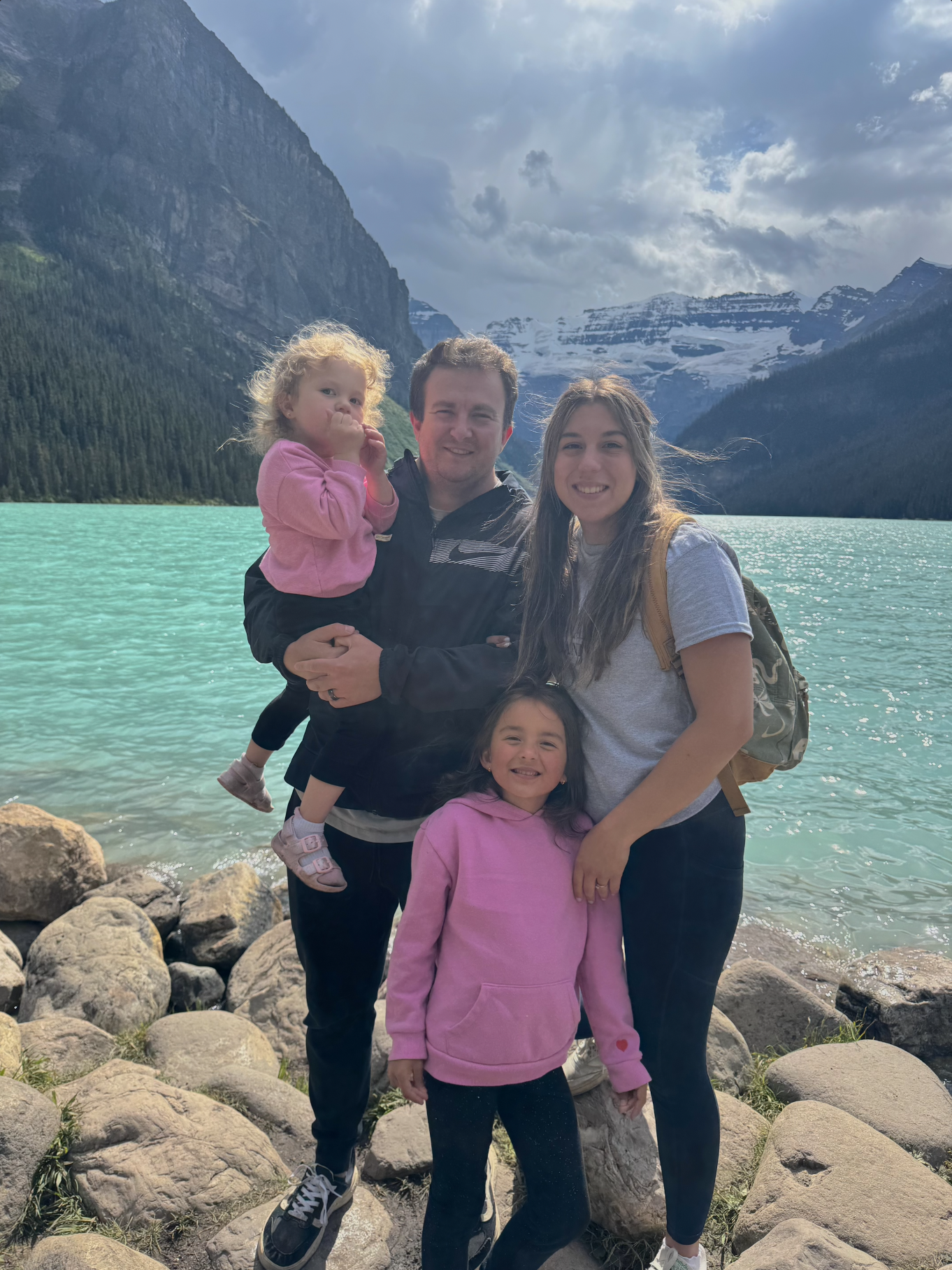 travel advisor arliss and her husband and two small daughters standing in a mountain and lake landscape