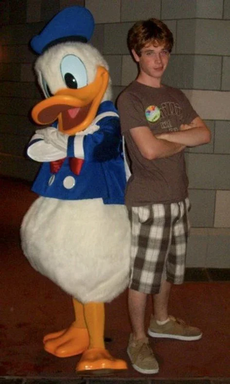 Young Aaron Guest posing with Donald Duck at Walt Disney World