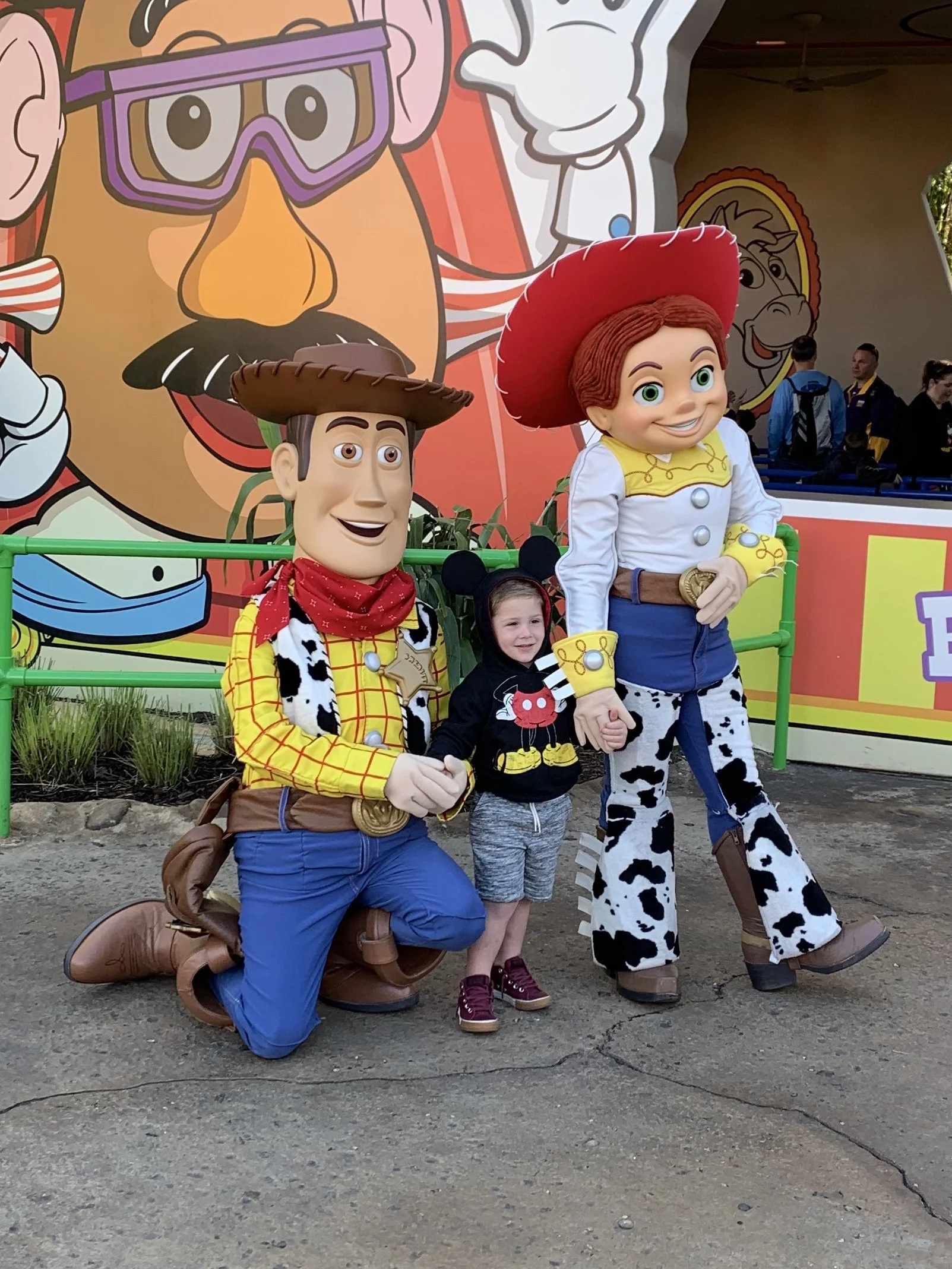 a little boy taking a picture with woody and jessie from toy story