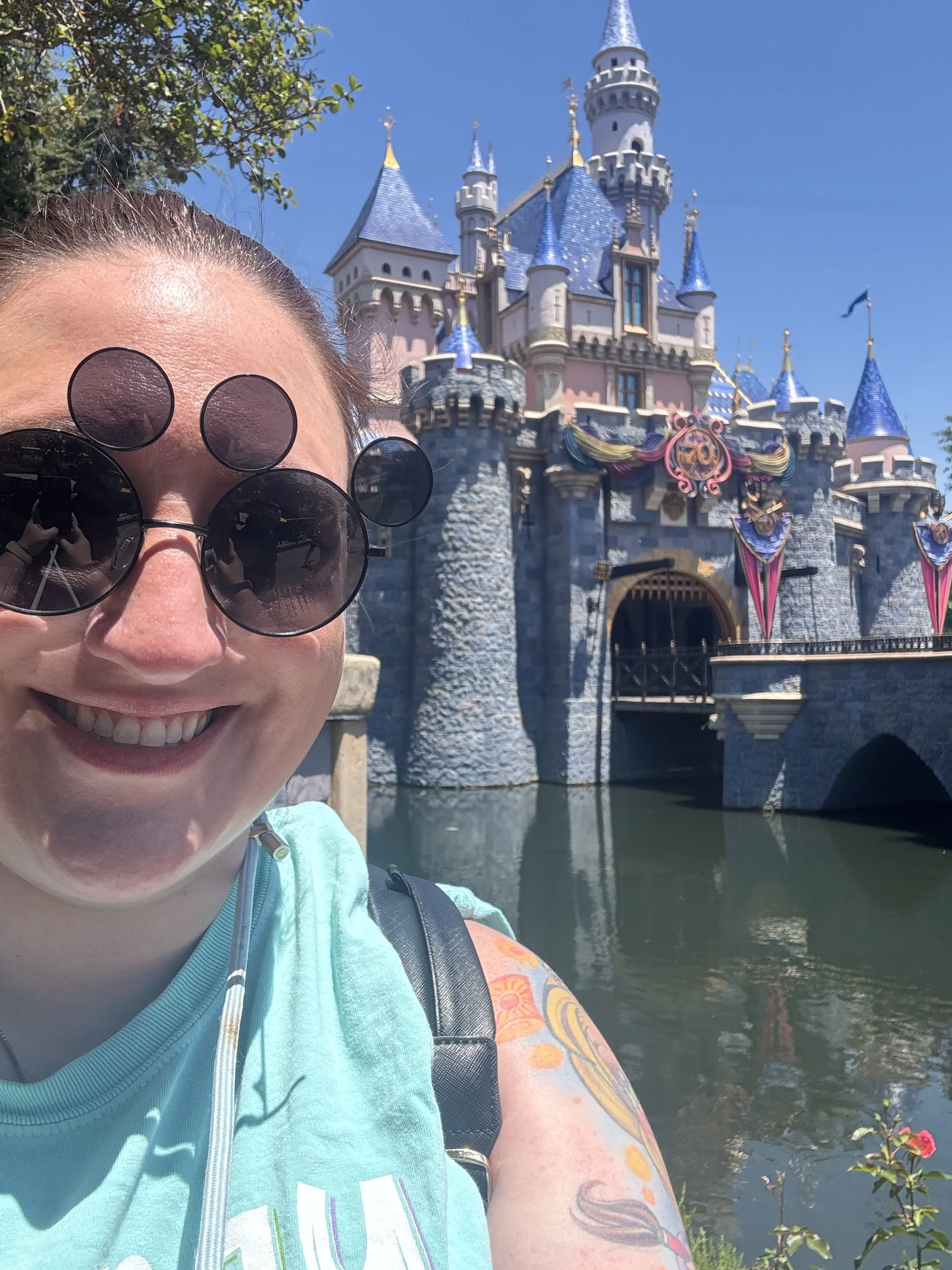 a woman smiling in front of the Disneyland castle