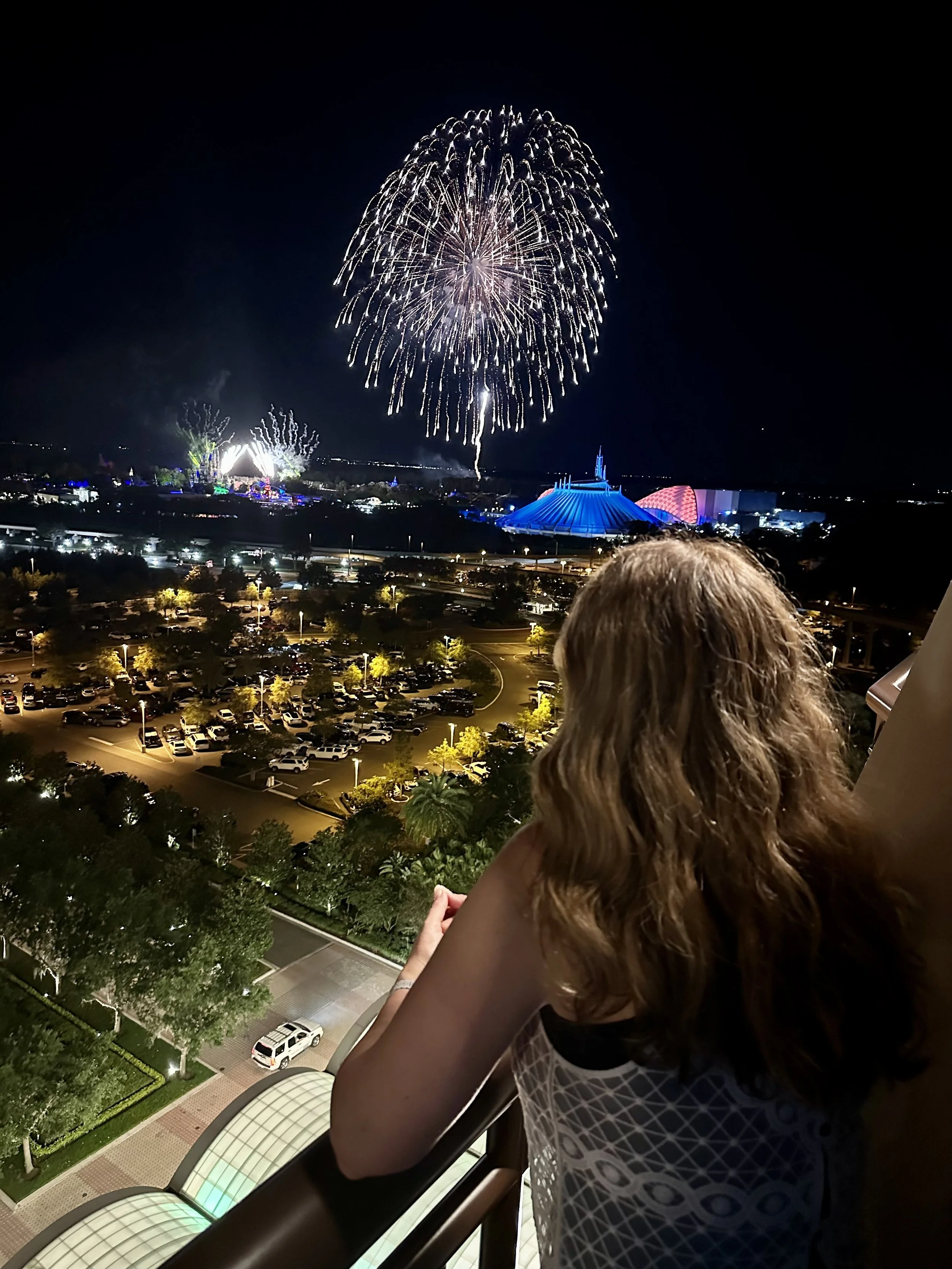A guest watches Magic Kingdom fireworks from a Club Level room balcony at Walt Disney World.