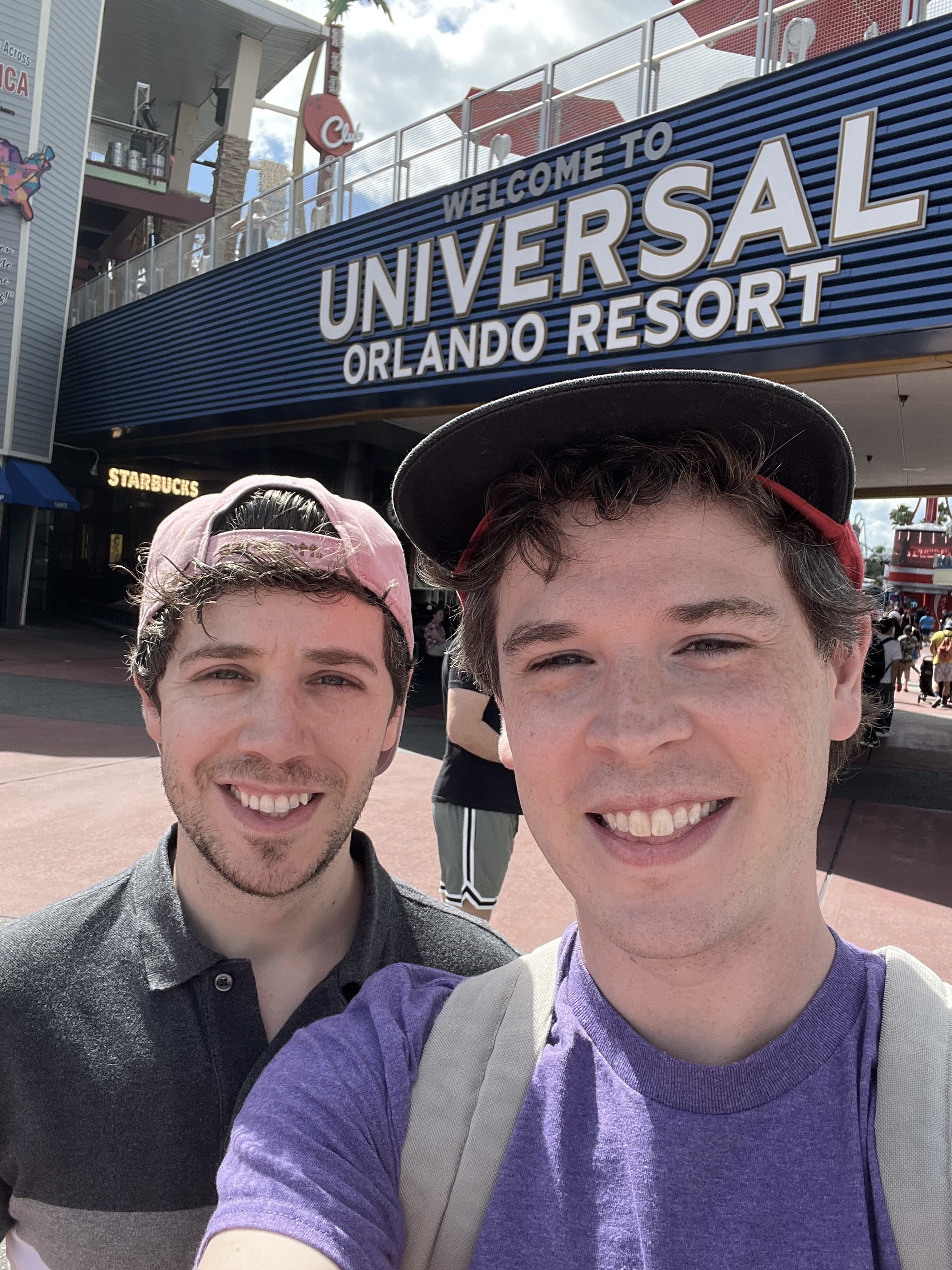 Aaron Guest and a friend smiling outside the entrance to Universal Orlando Resort.