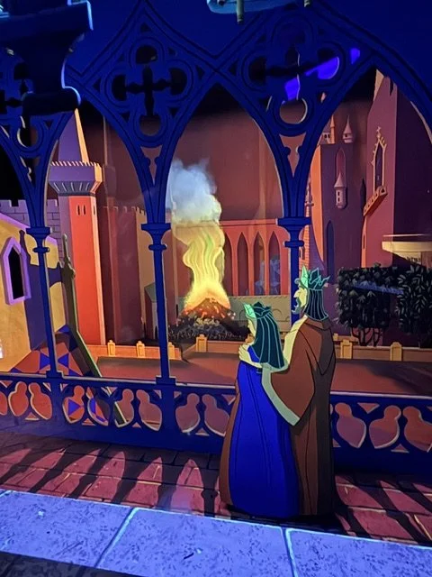 a king and queen looking at a fire