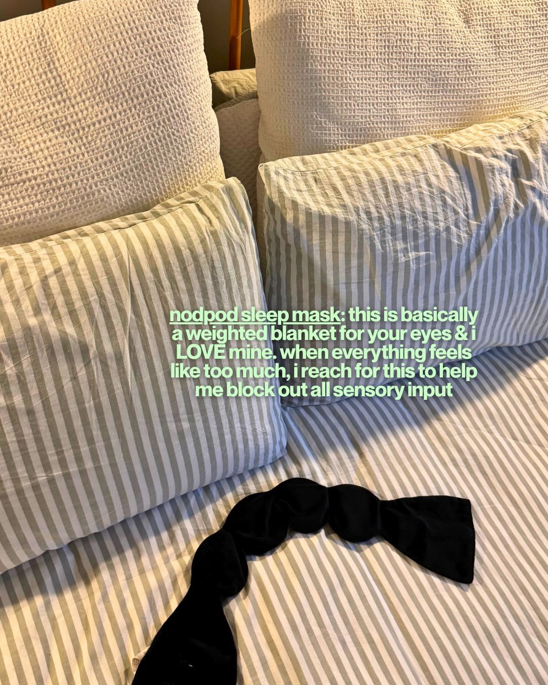 Black Nodpod weighted sleep mask lying on a striped bed
