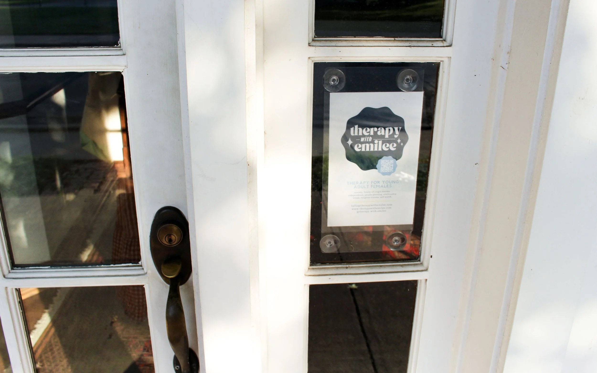 White door with glass panes and a lock, with a sign that reads 'therapy with emilee'.