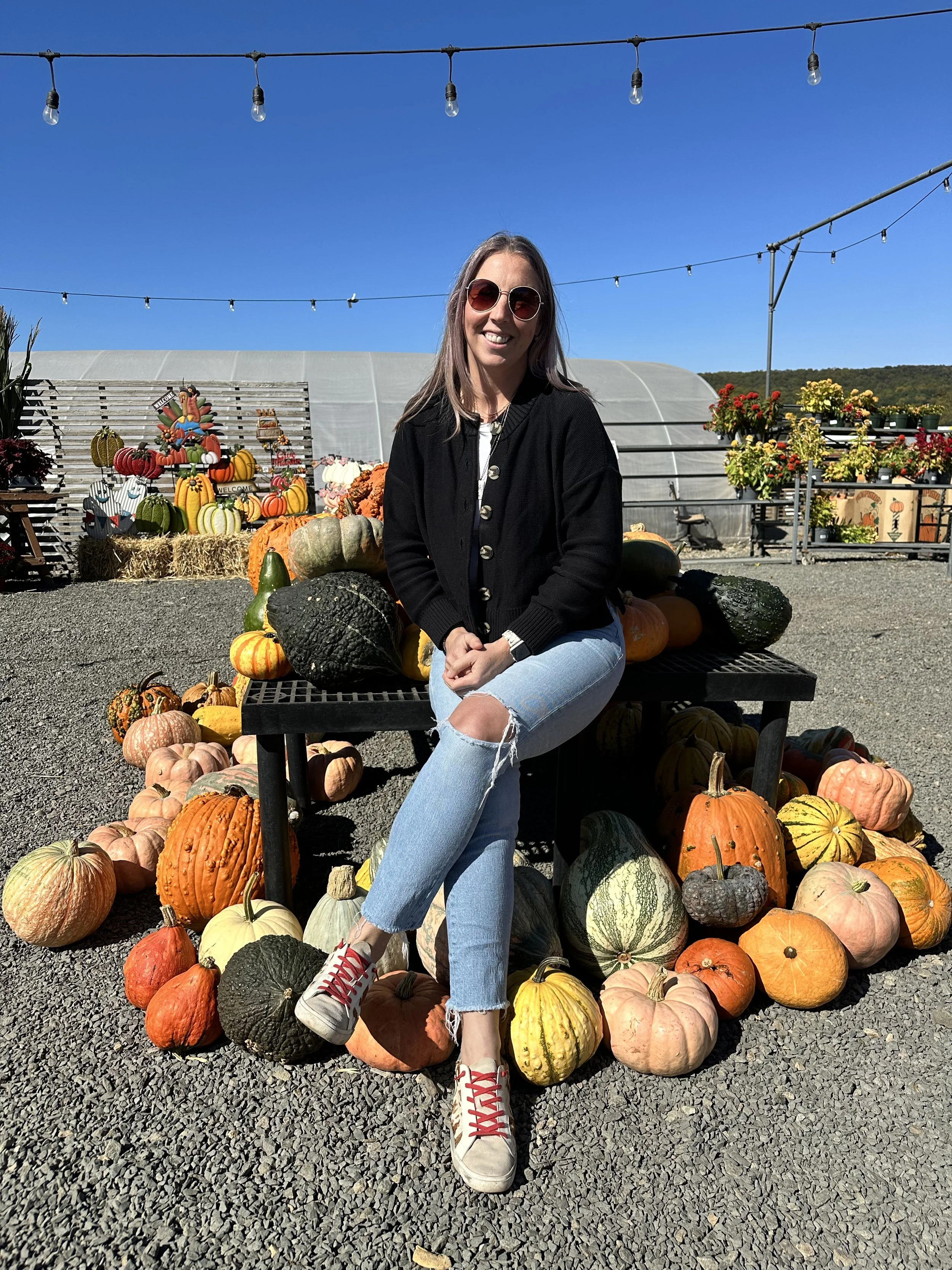 Elia sitting on a bench in a pumpkin patch