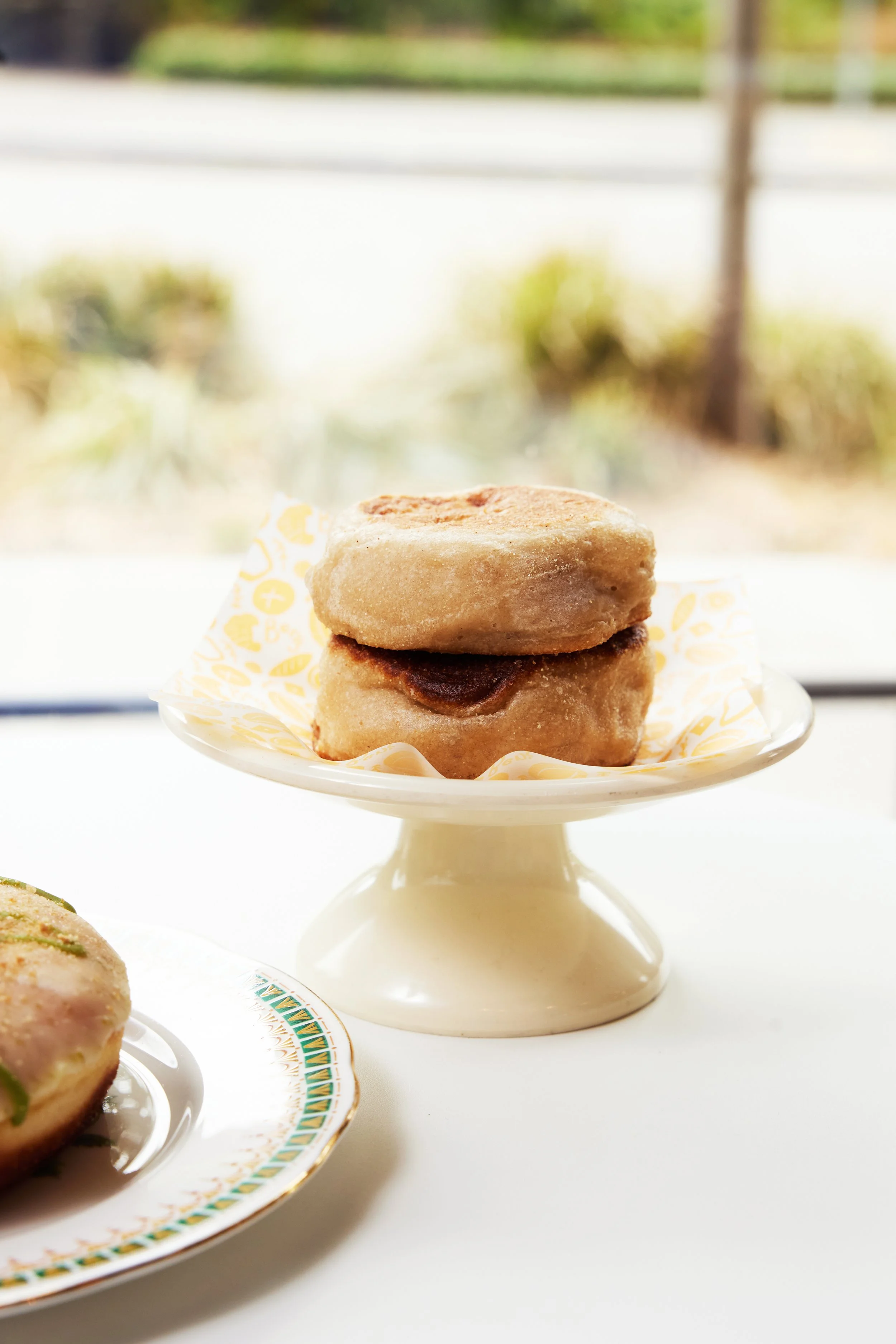 Two sourdough english muffins sitting on top of a mini pedestal.