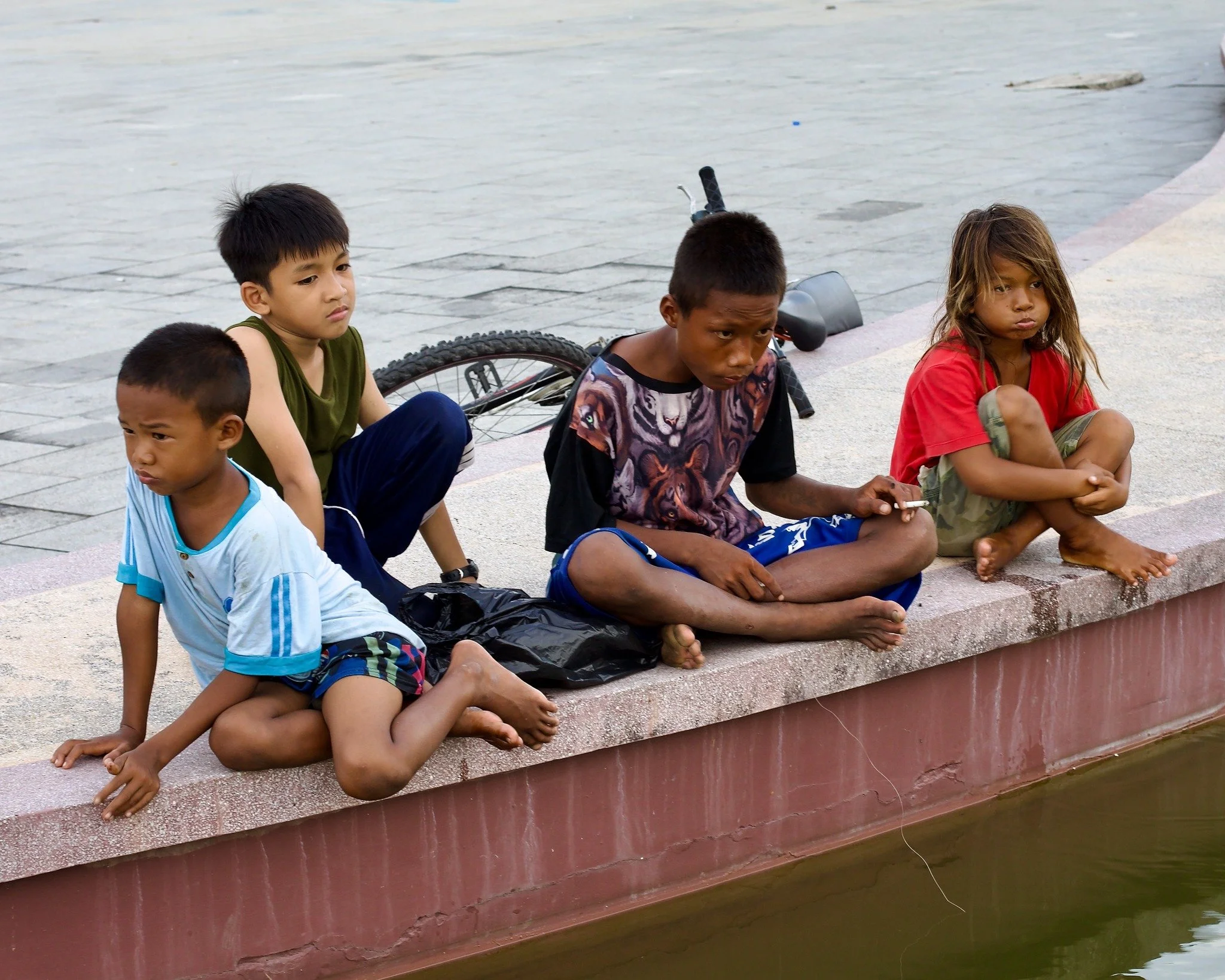 Director Kevin recently took this photo in Cambodia. These street kids are hanging out at a park. You can see one is smoking. The girl on the right badly needs a bath and a comb. Sitting in the sun, watching people play and eat, you wonder what's in 