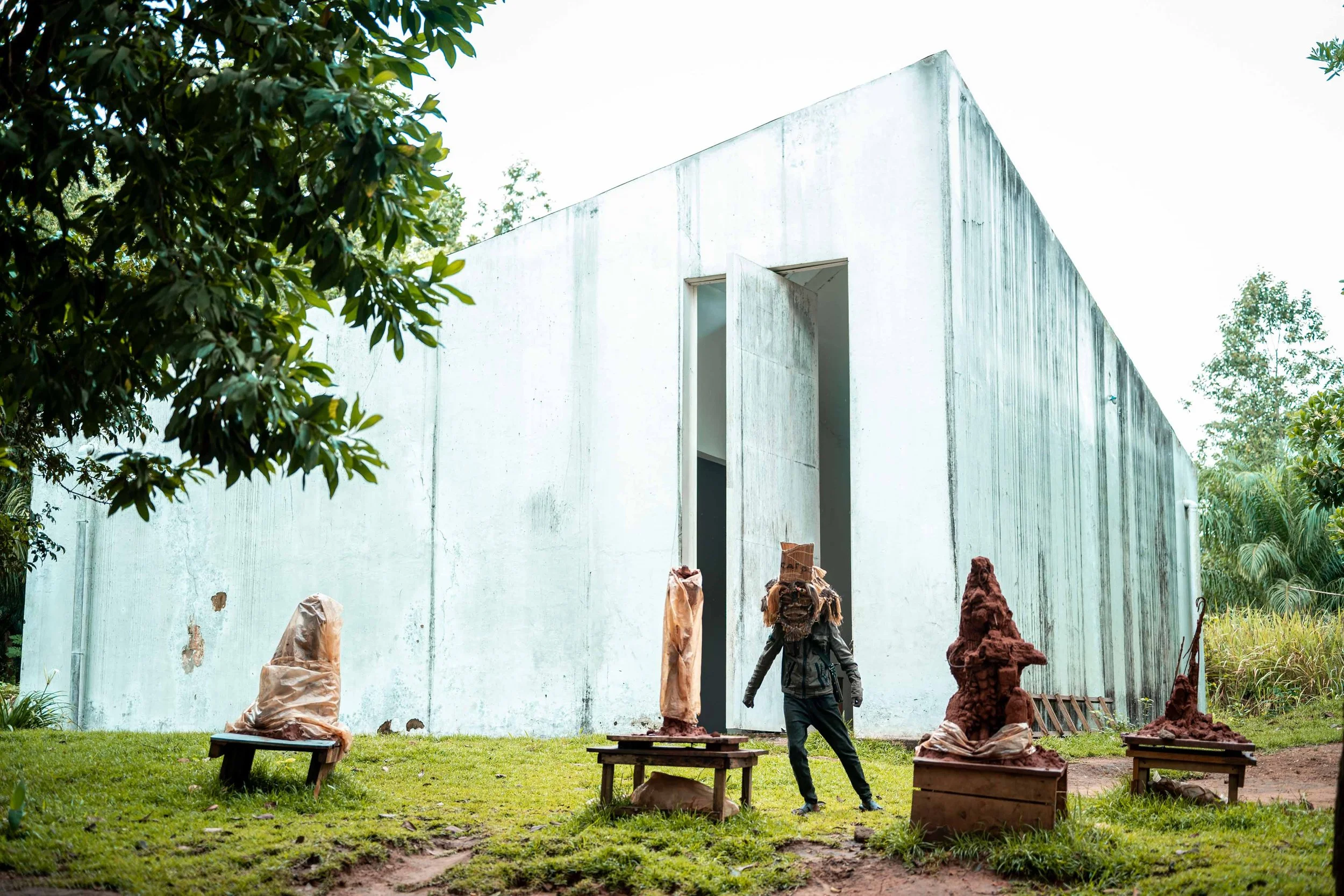 Artist and performer Daniel Mufunzi wears the Mbunya mask, a symbol of power, in front of the White Cube Museum. Lusanga, Democratic Republic of the Congo, February 2025.