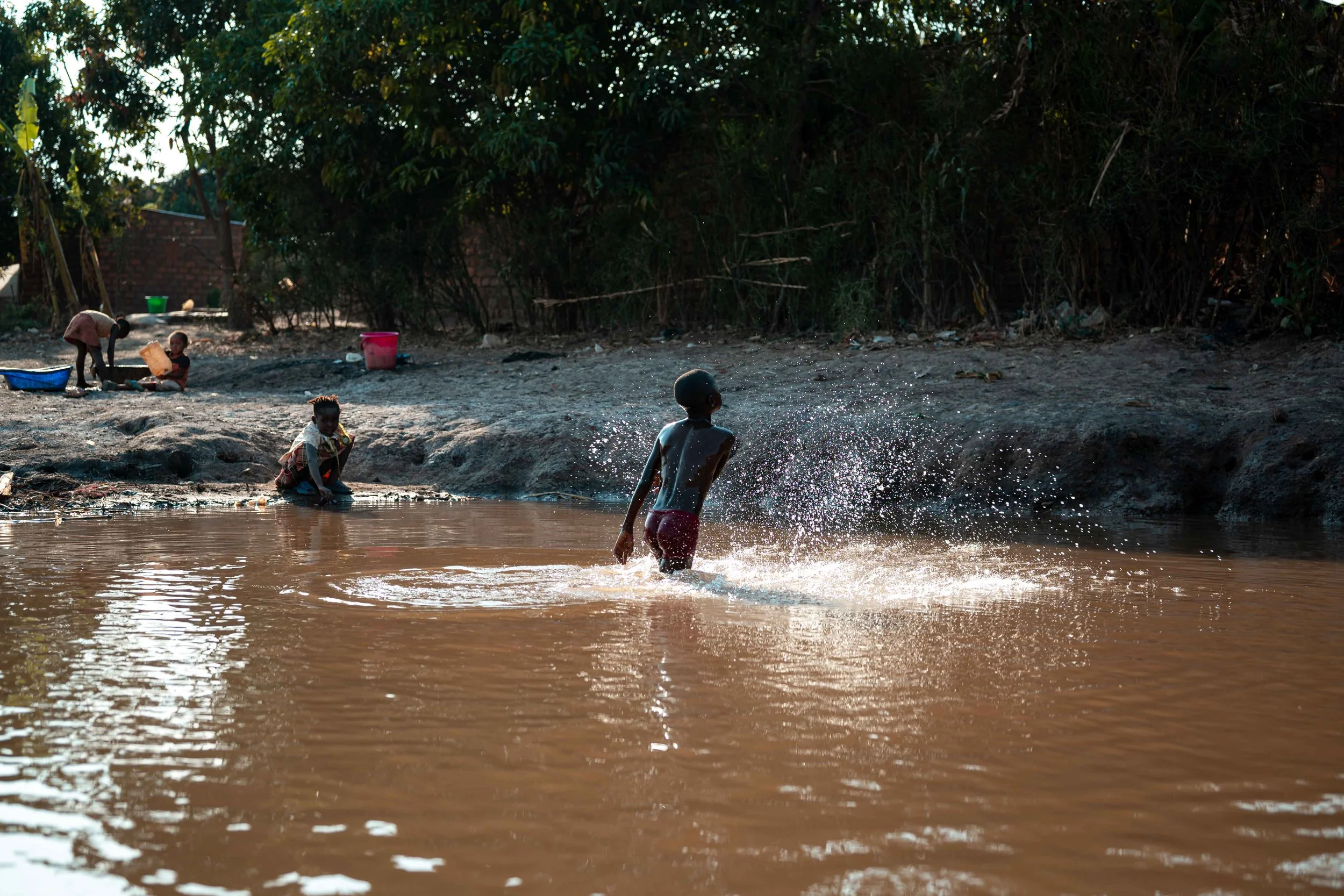 A child plays in a river in Manomapia. The waterway has been polluted by toxic waste from Tenke Fungurume Mining. A massive fish die-off was reported one week ago. Lualaba Province, Democratic Republic of the Congo.