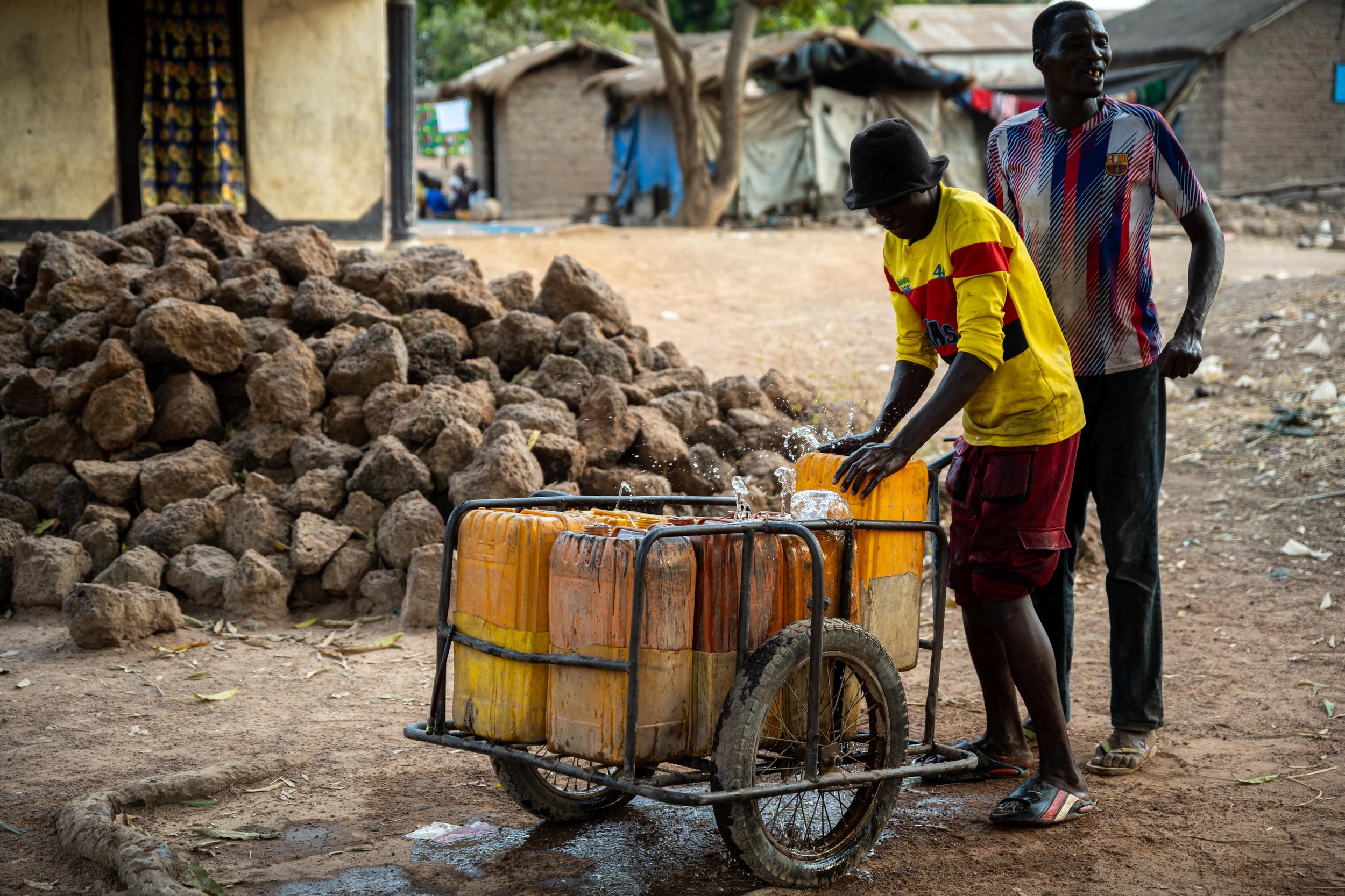 Deux hommes prêts à embarquer leurs bidons remplis d’eau qu’ils viennent de collecter à Markounda, République centrafricaine, décembre 2025.