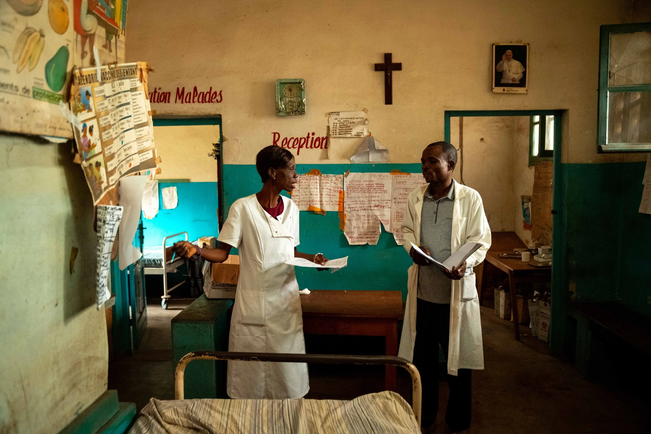 Nurse Maguy Mbadikou speaks with her colleague Willy Kimbala in the hall of the Mukasa health center, in Kwilu, Democratic Republic of Congo, September 2025.