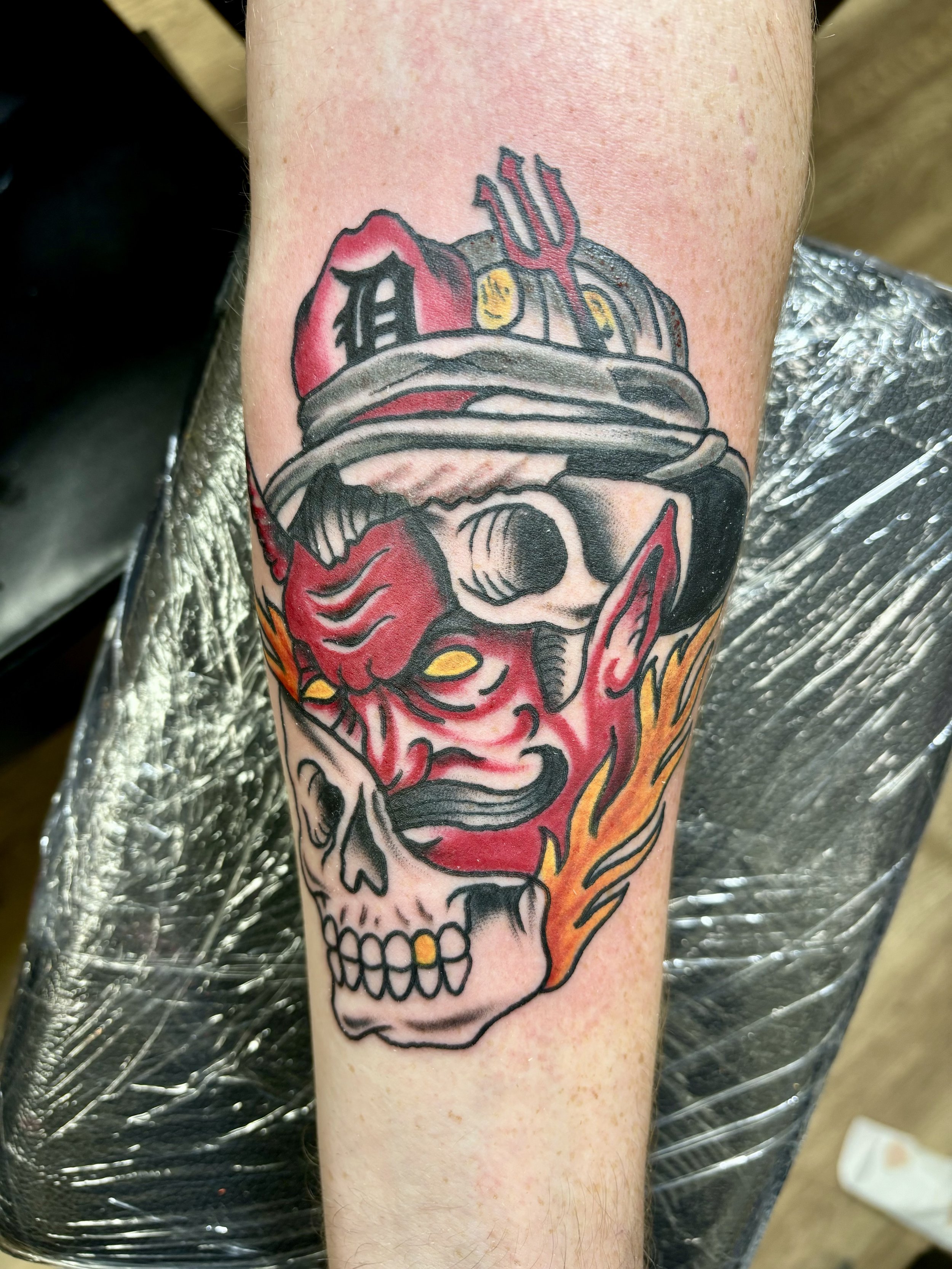Tattoo of a red devil and skull merged design on arm