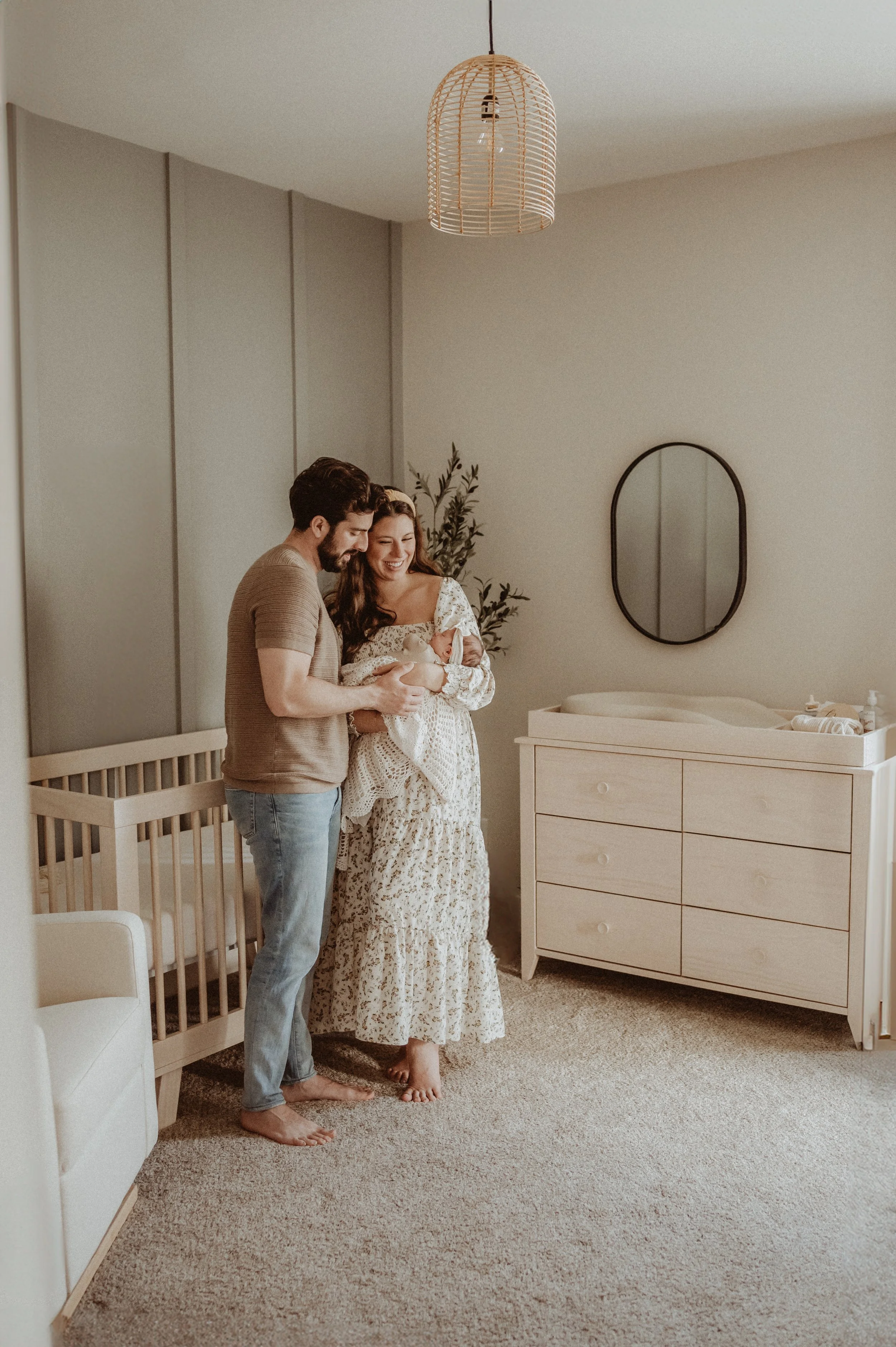 Mother and father snuggling with their new baby in nursery