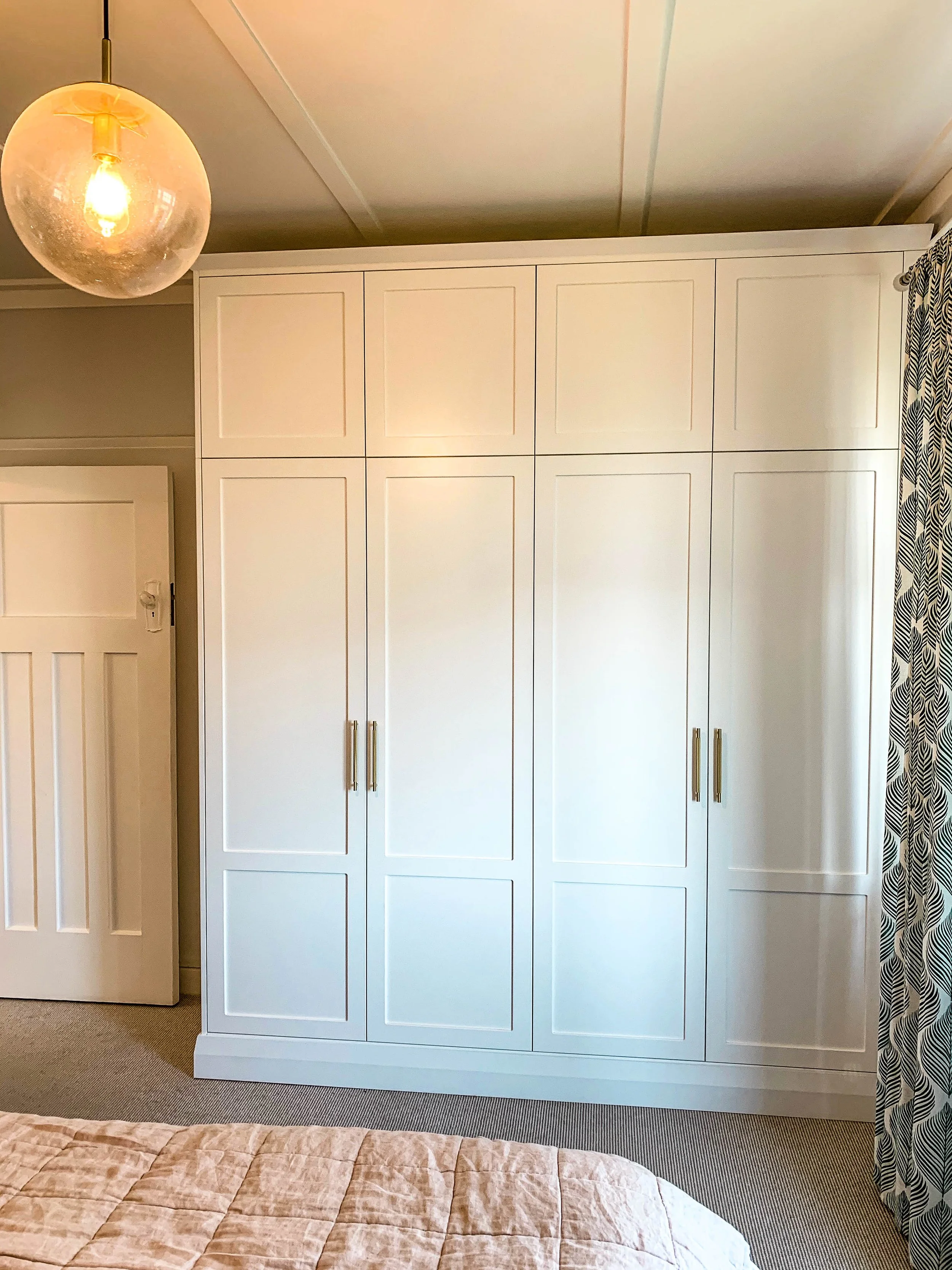 White panel door wardrobe with white bedroom door visible and patterned curtain 