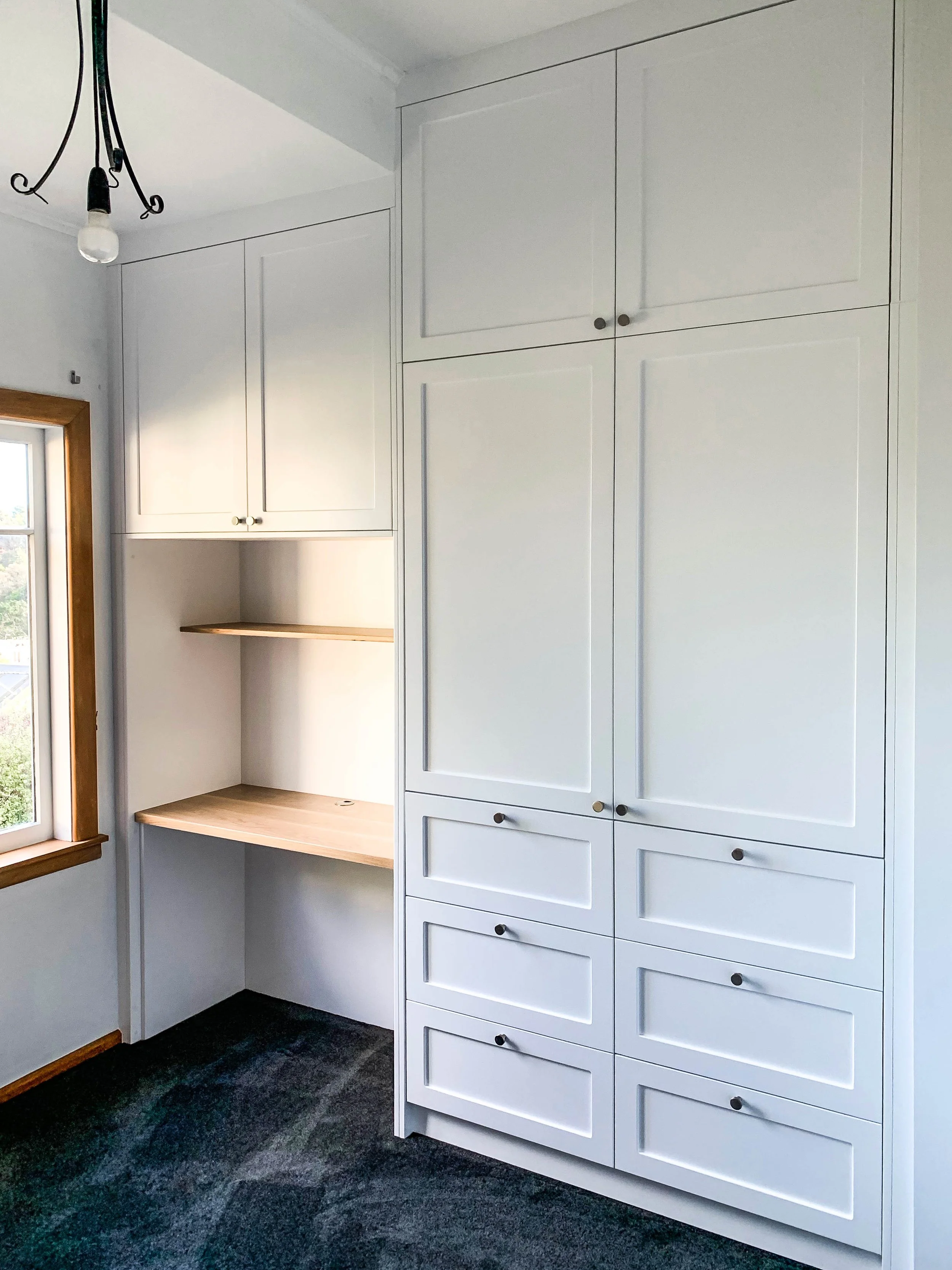 White panel wardrobe with chrome handles and desk pace with wooden shelves