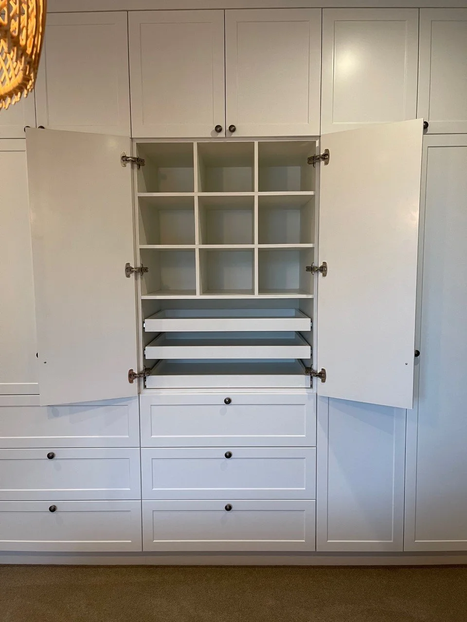 Panel door wardrobe with cabinet doors open showing cubby spaces and pull out shelves