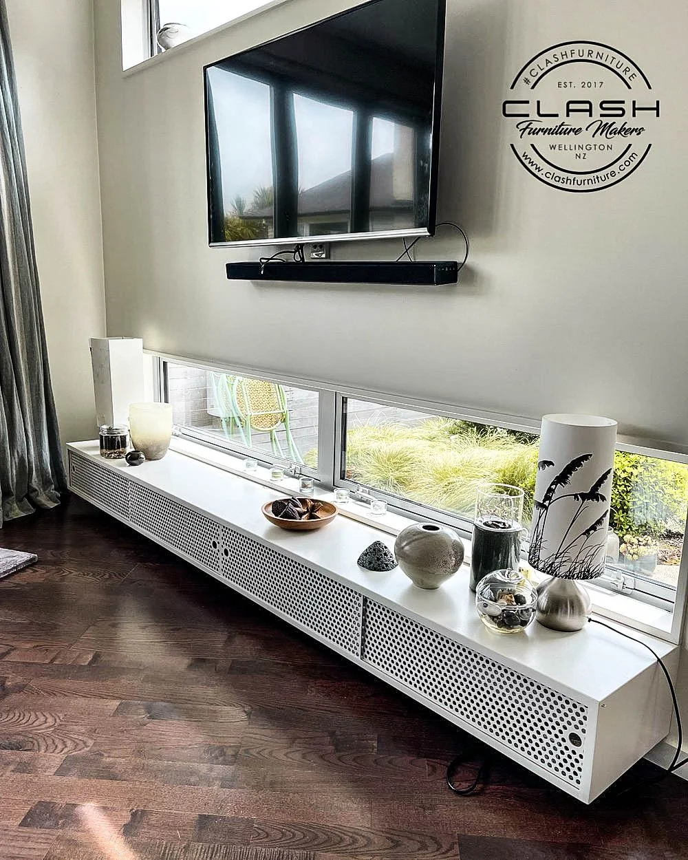 White melteca entertainment unit wall hung below two windows displaying lamps and vases