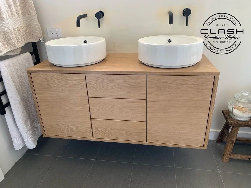 Timber two sink basin with a cabinet either end and three drawers in the middle. Black tapware on the wall and a power point 