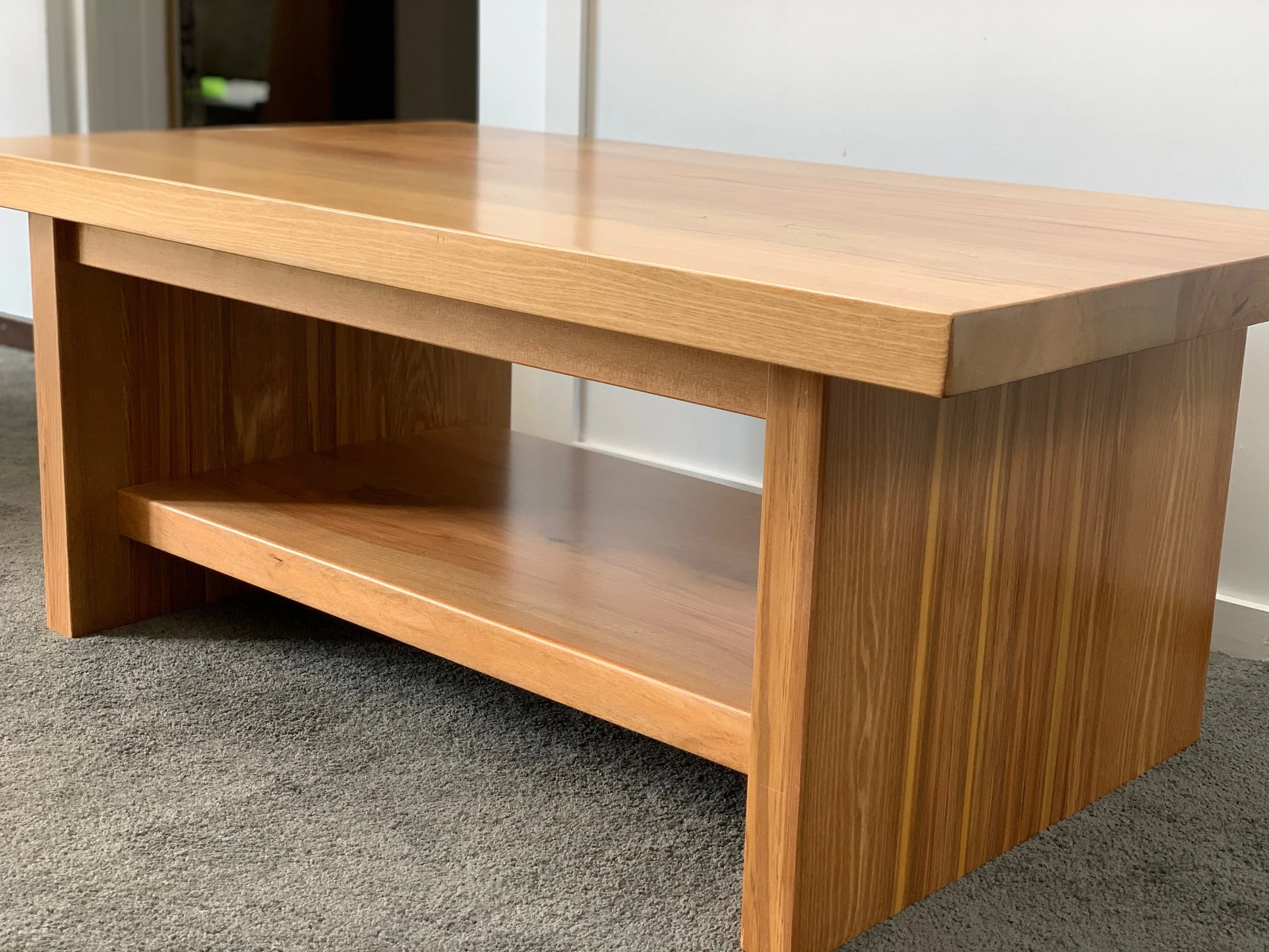 Wooden coffee table with low shelf sitting on grey carpet
