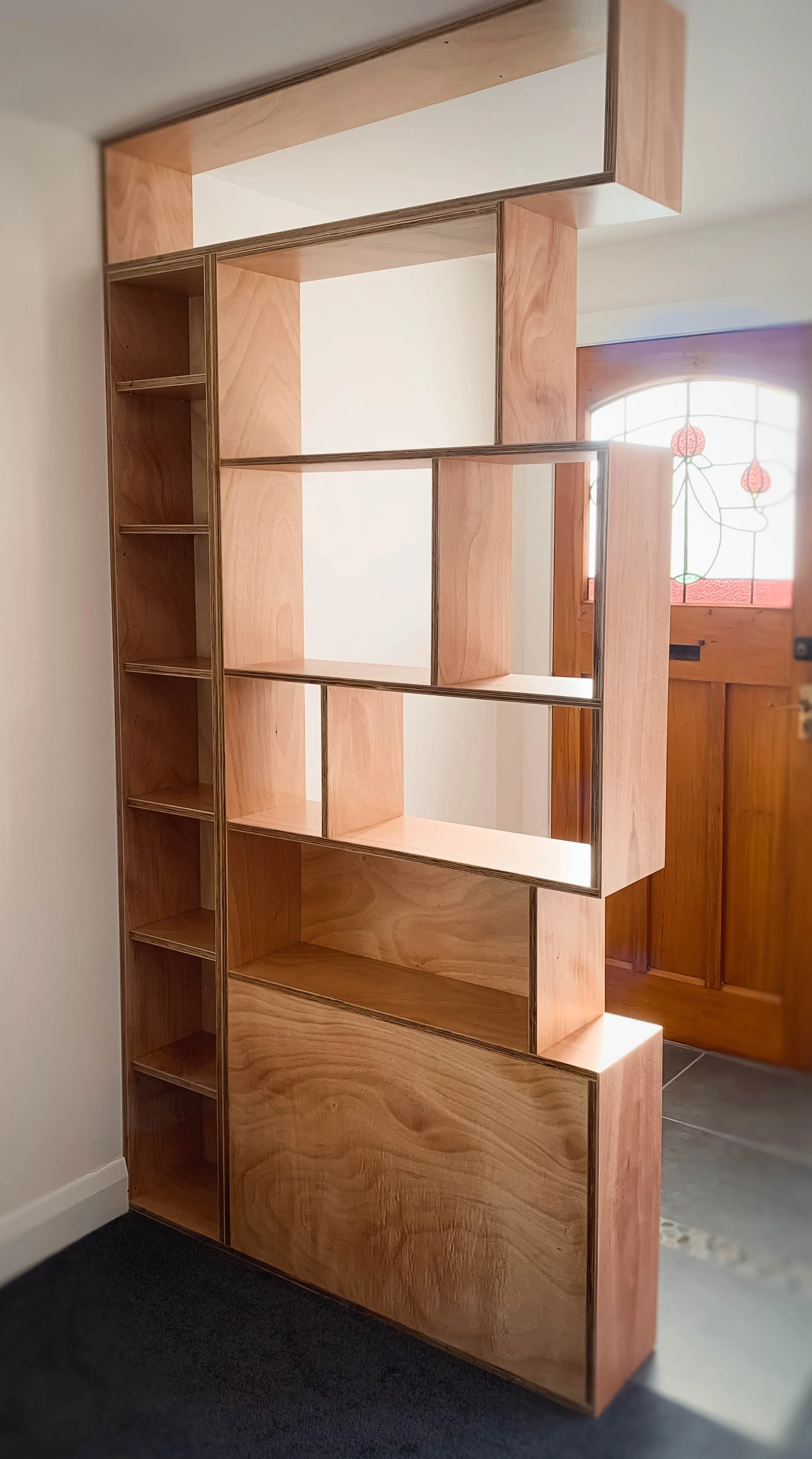 Plywood room divider with front door with stained glass in back ground