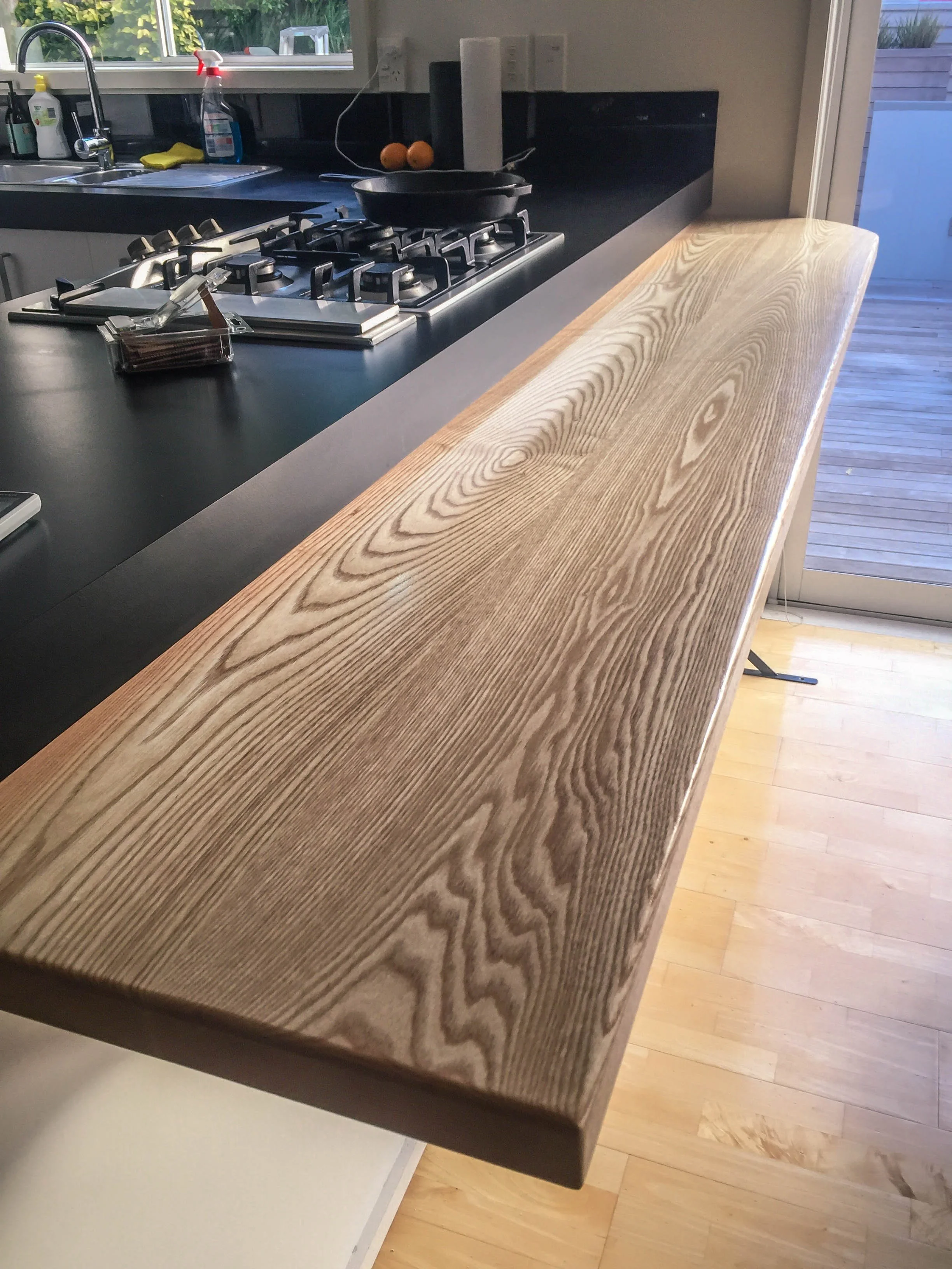Solid wood kitchen bar top with grain visible and light wooden floors  
