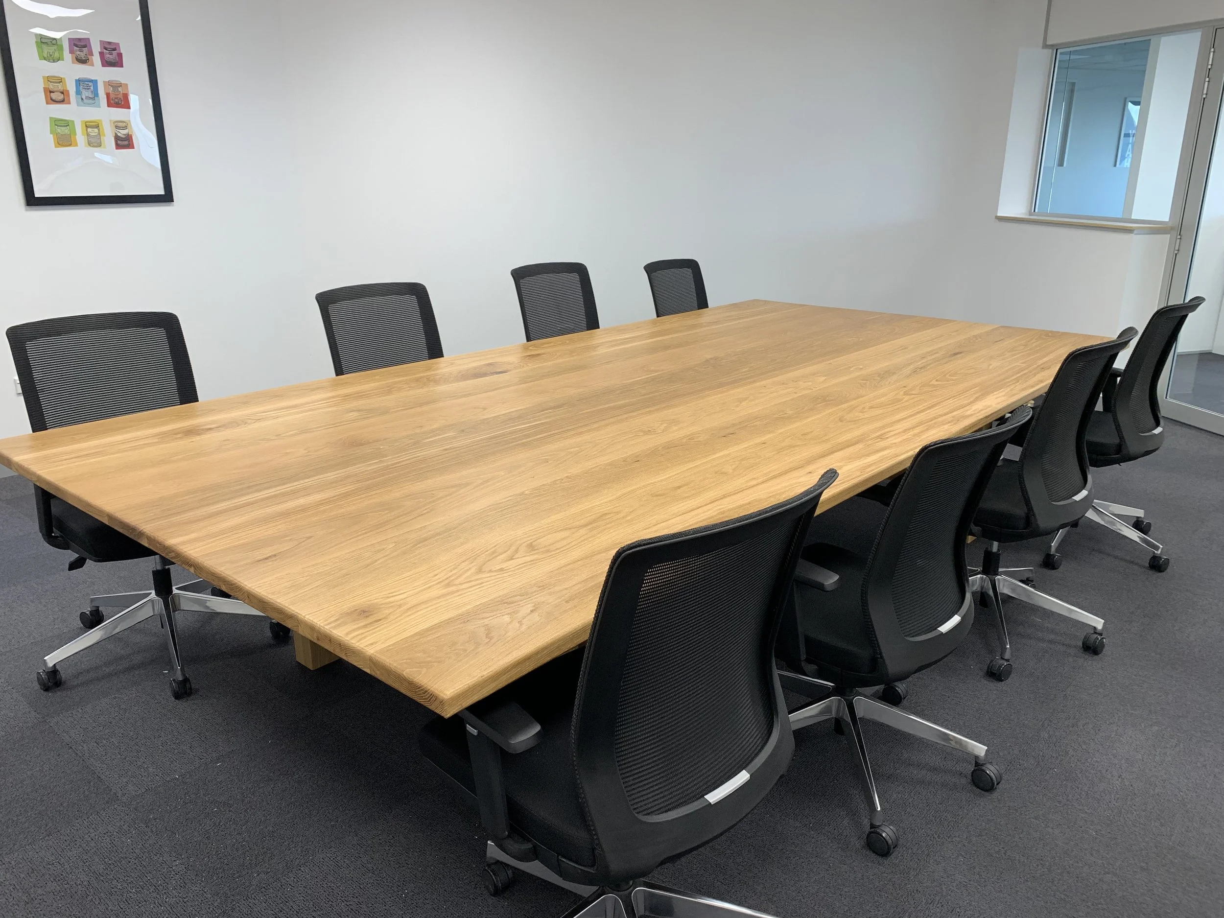 Large board room table with eight black desk chairs in room 