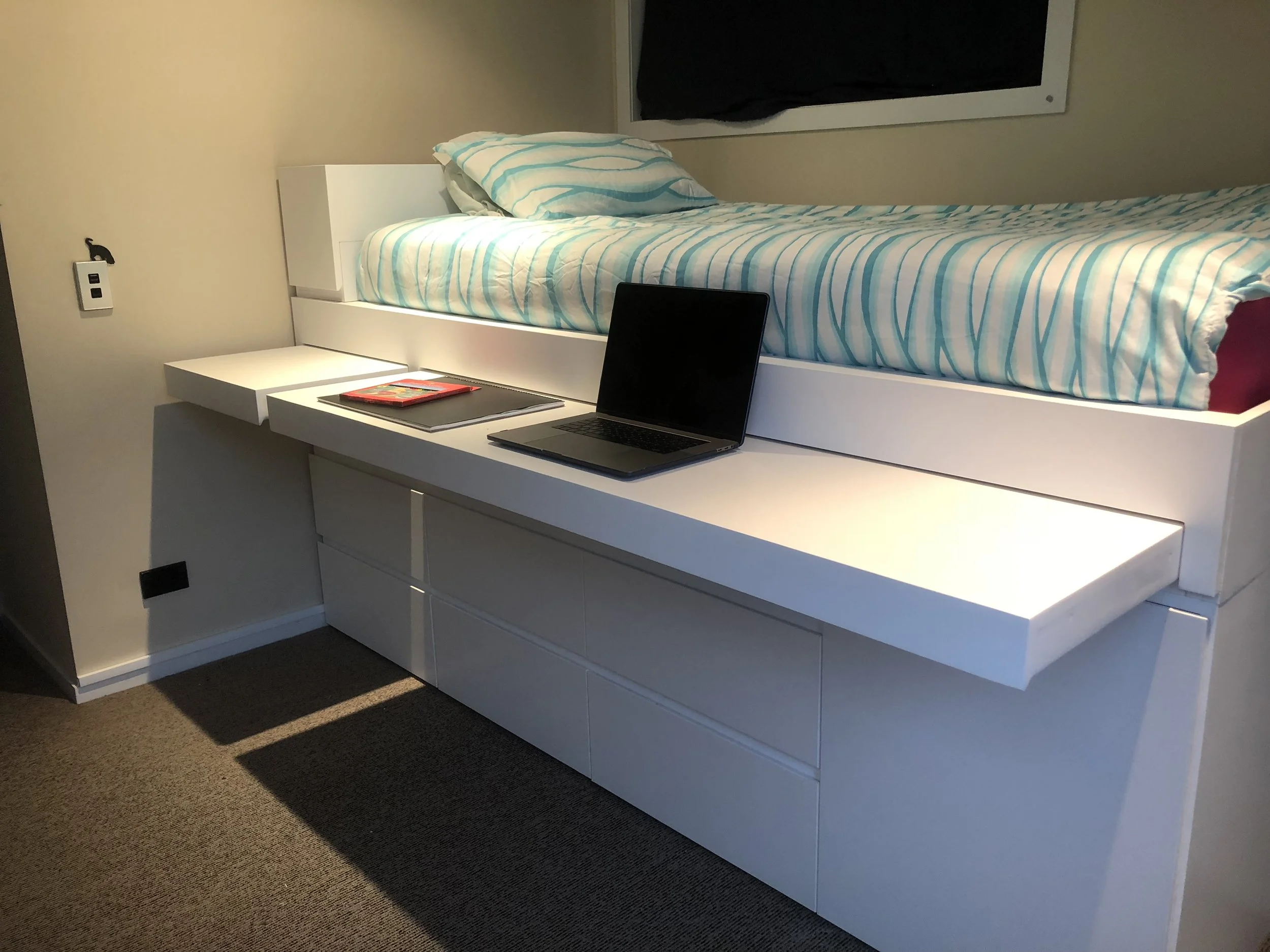 White bed base with built in storagender bed base. Consisting of a pull out desk, built in drawers and a shoe rack. Blue and white patterned duvet and pillow case cover matrace