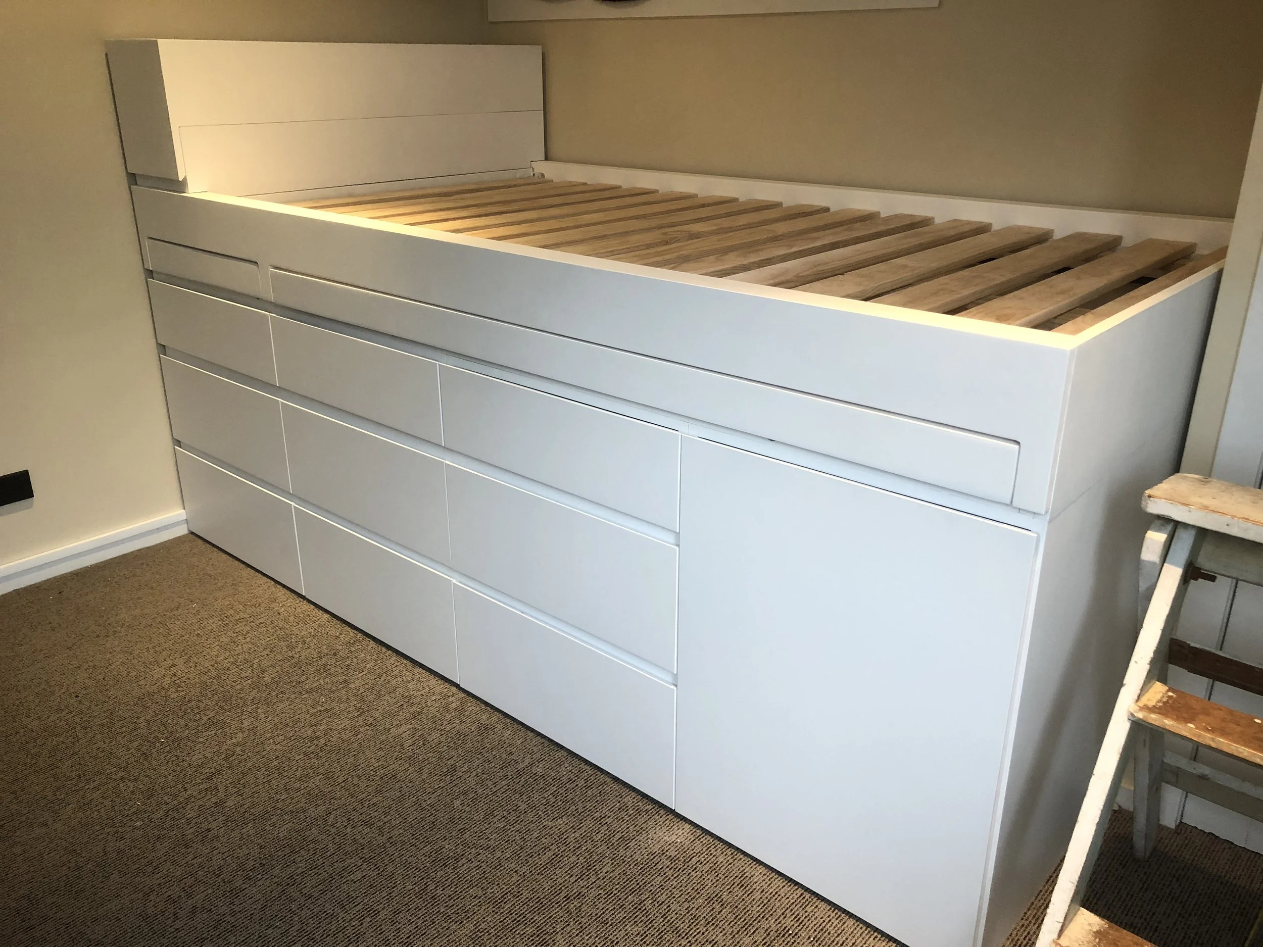 White bed base with built in storage under bed base. Consisting of a pull out desk, built in drawers and a shoe rack