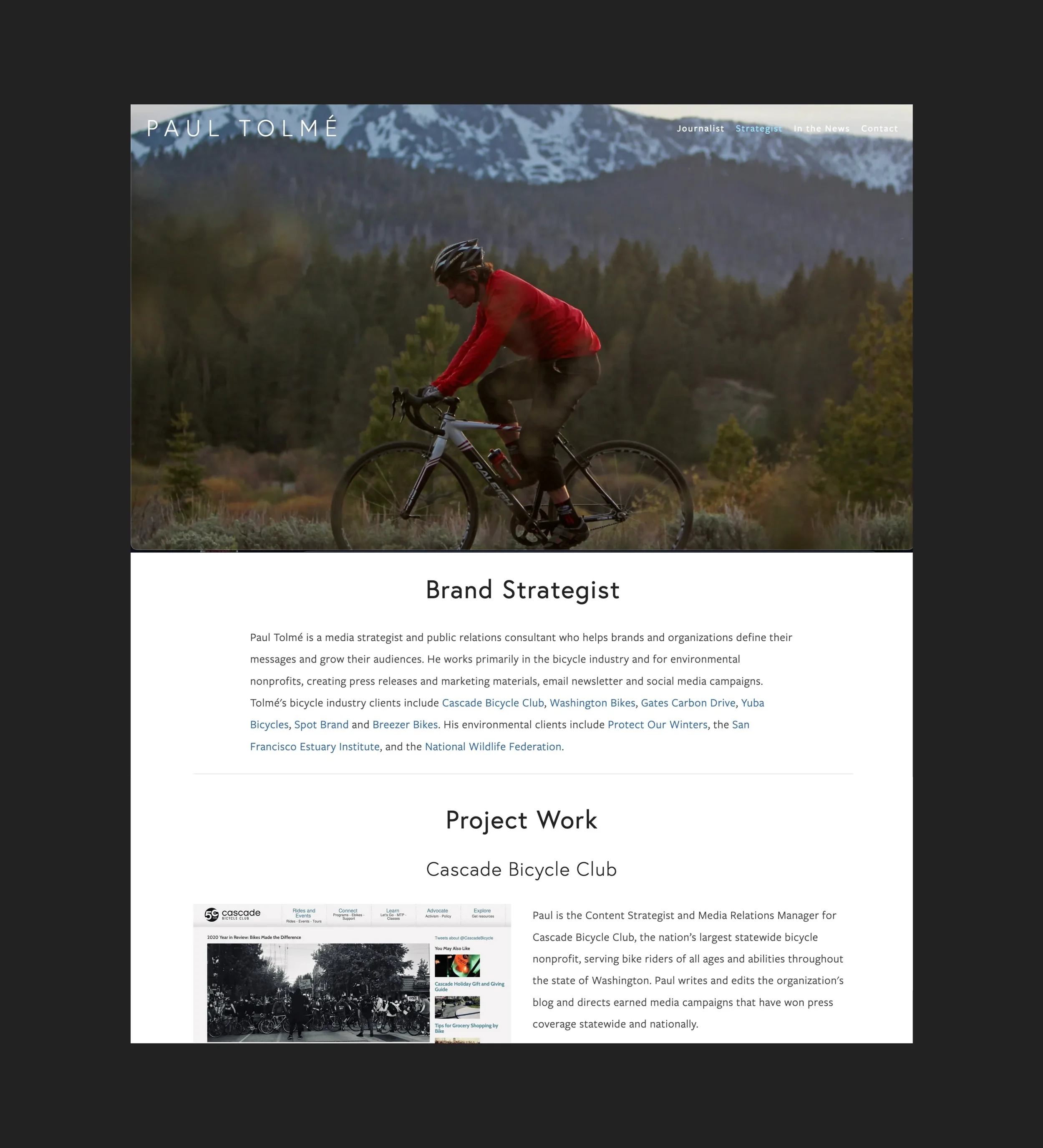 A person riding a bicycle through a natural landscape with mountains and trees, wearing a red jacket and a helmet during daylight hours.