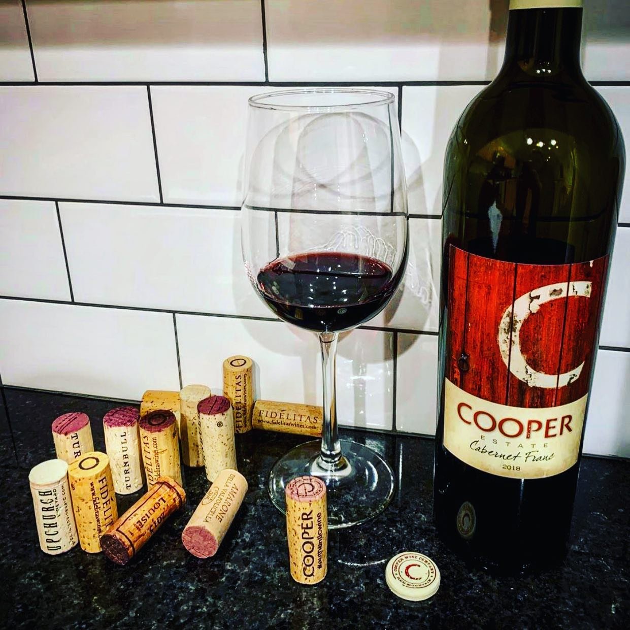 Cooper bottle of wine, glass of wine, and wine corks