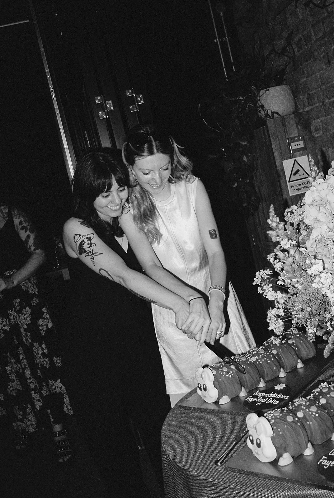 Bride cut cake while smiling captured on film in black and white.