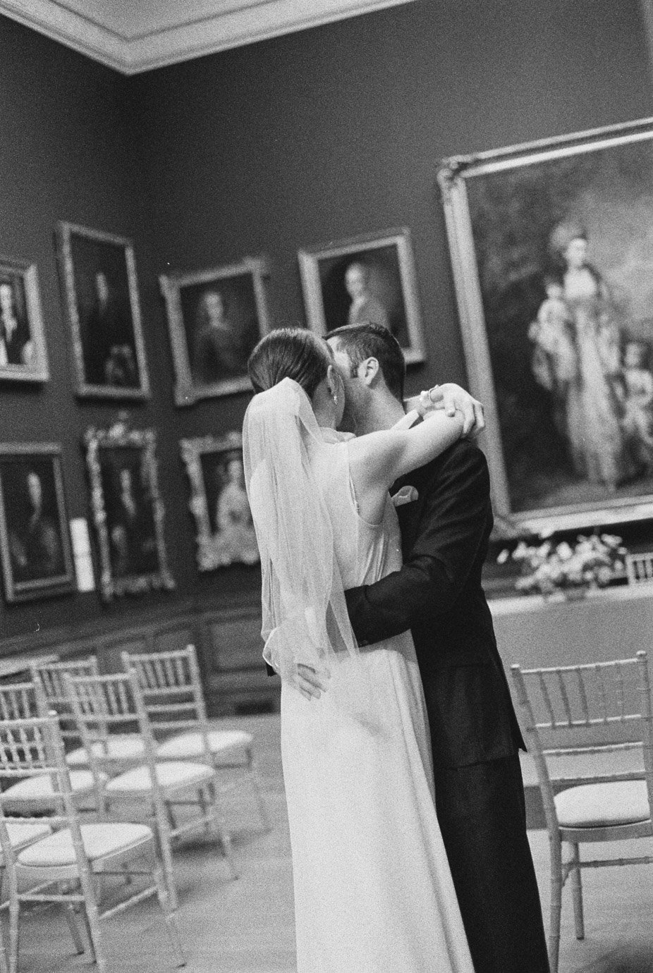 Bride and groom embracing on BW film inside the Soane gallery in Dulwich Picture Gallery.