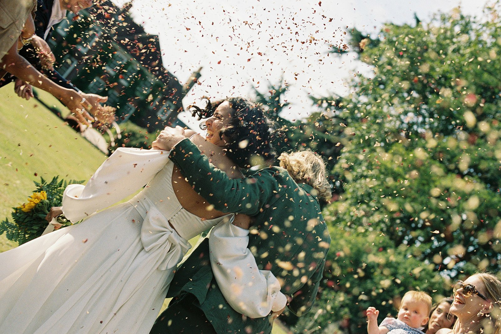 A bride and groom hold each other smile as guests throw confetti outside a Montpellier manor.