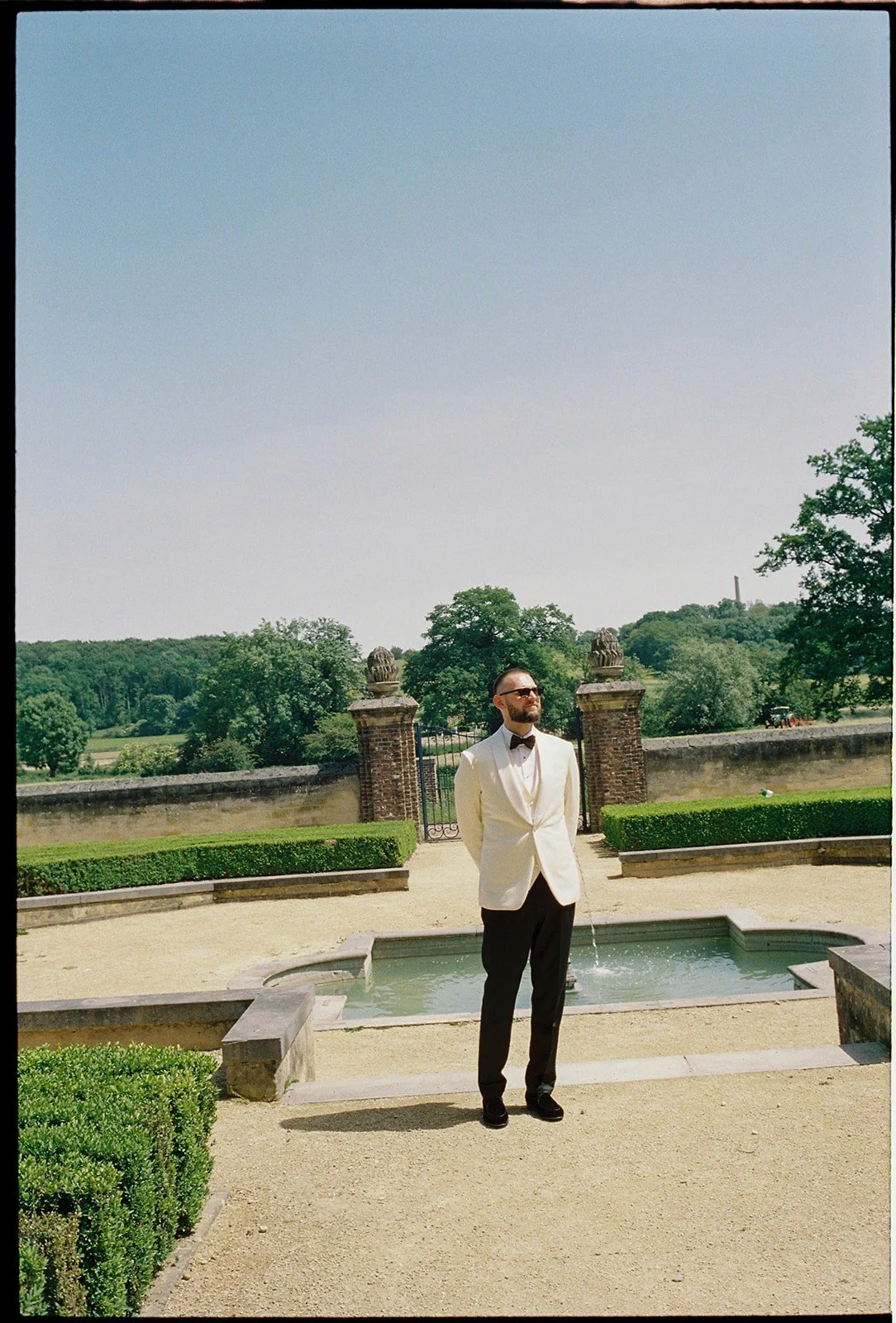 Groom smiles while waiting for bride at first look at the Baroque gardens at Chateau Neercanne wedding