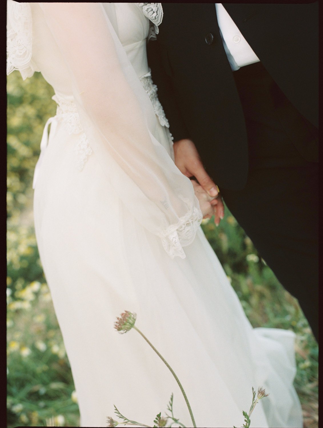 the bride wearing a vintage wedding dress with lace details, holding hands with the groom by Algarve film wedding photographer
