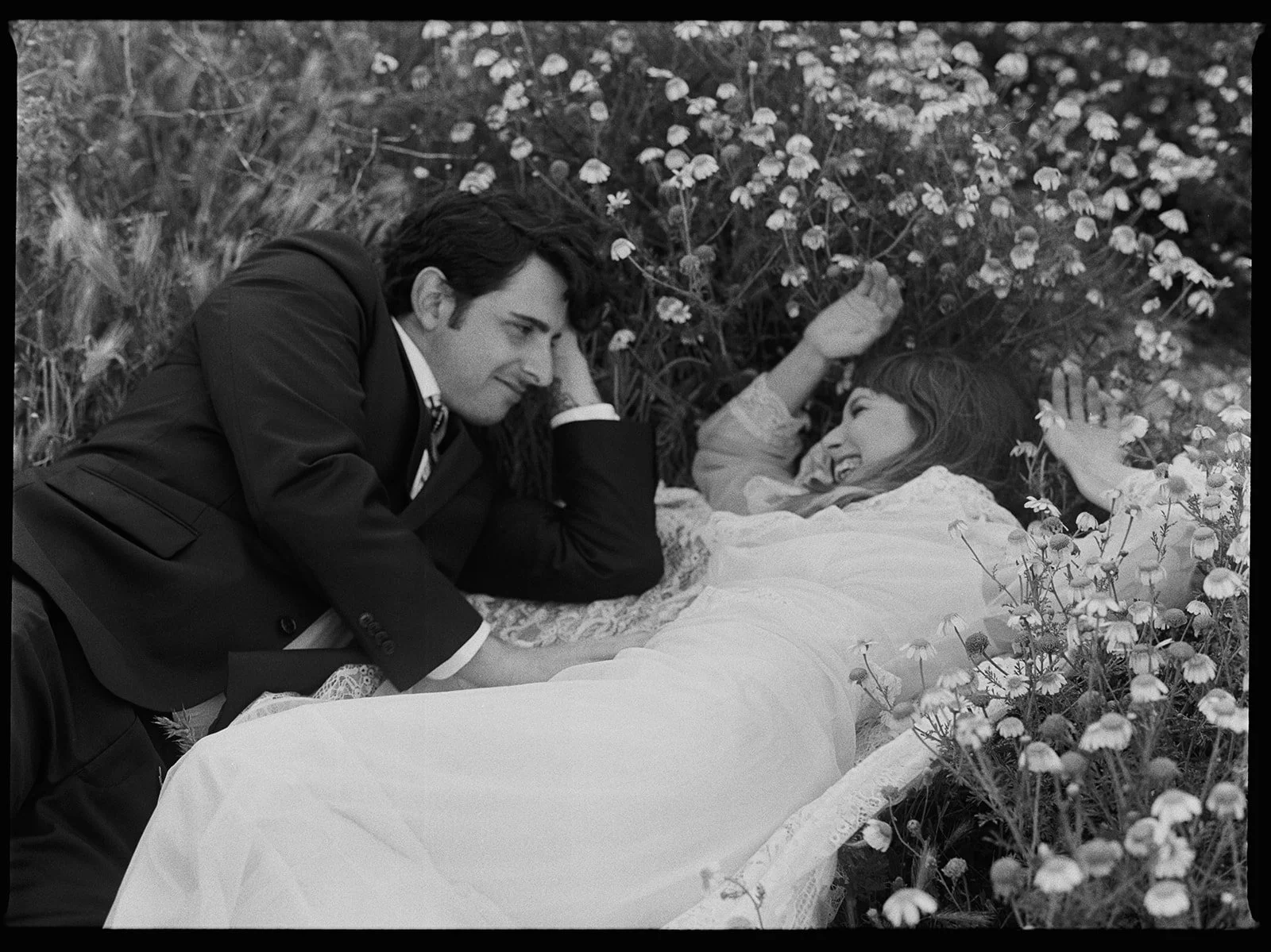 Bride and groom laying on flower field in black and white medium format film by London film wedding photographer