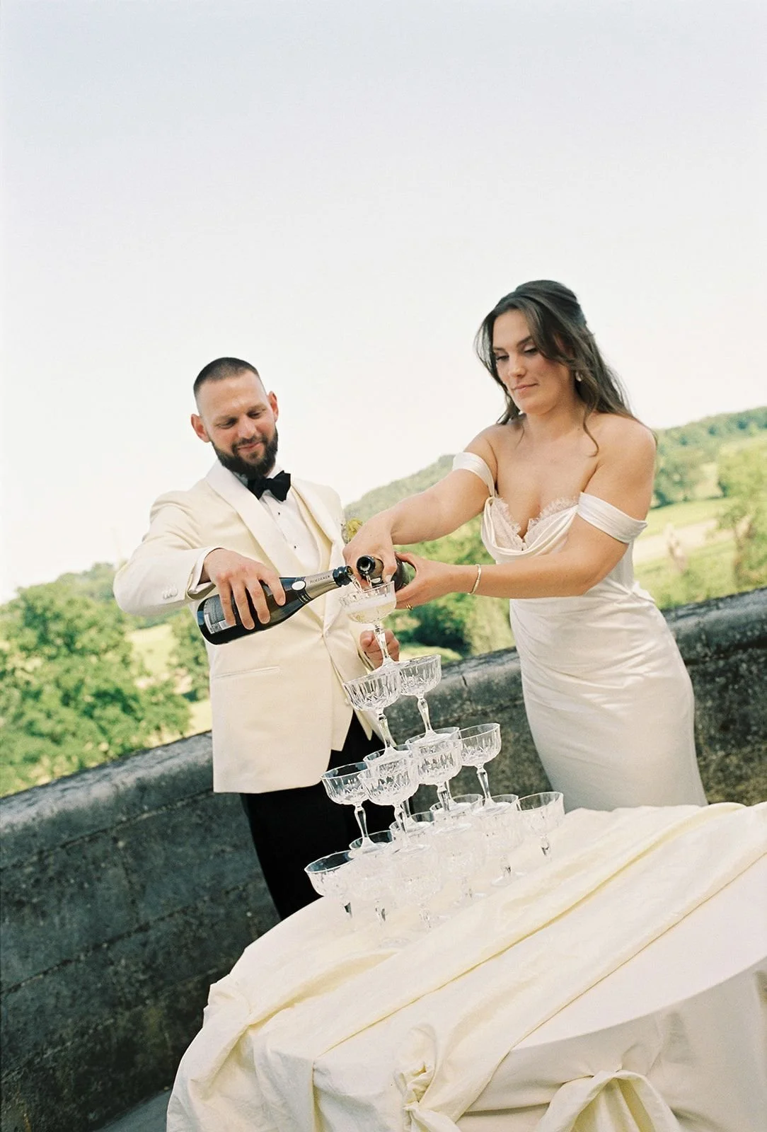 Bride and groom pour bottle at champagne tower in Chateau Neercane wedding