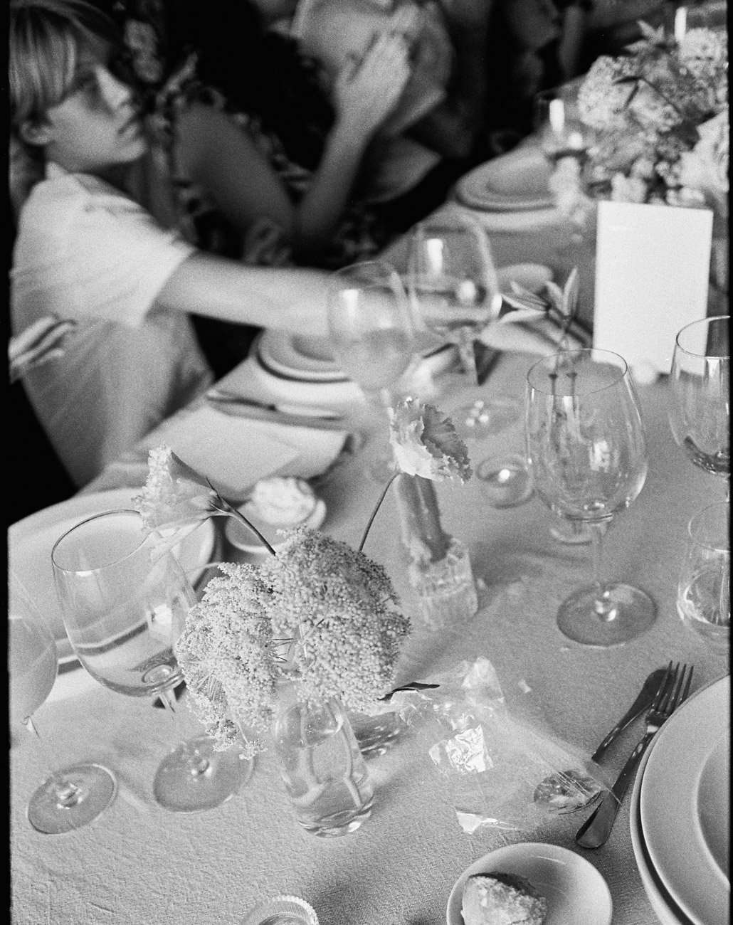 Artistic and timeless BW wedding dinner scene showing a young boy at the table, photographed on film by a Lisbon documentary wedding photographer