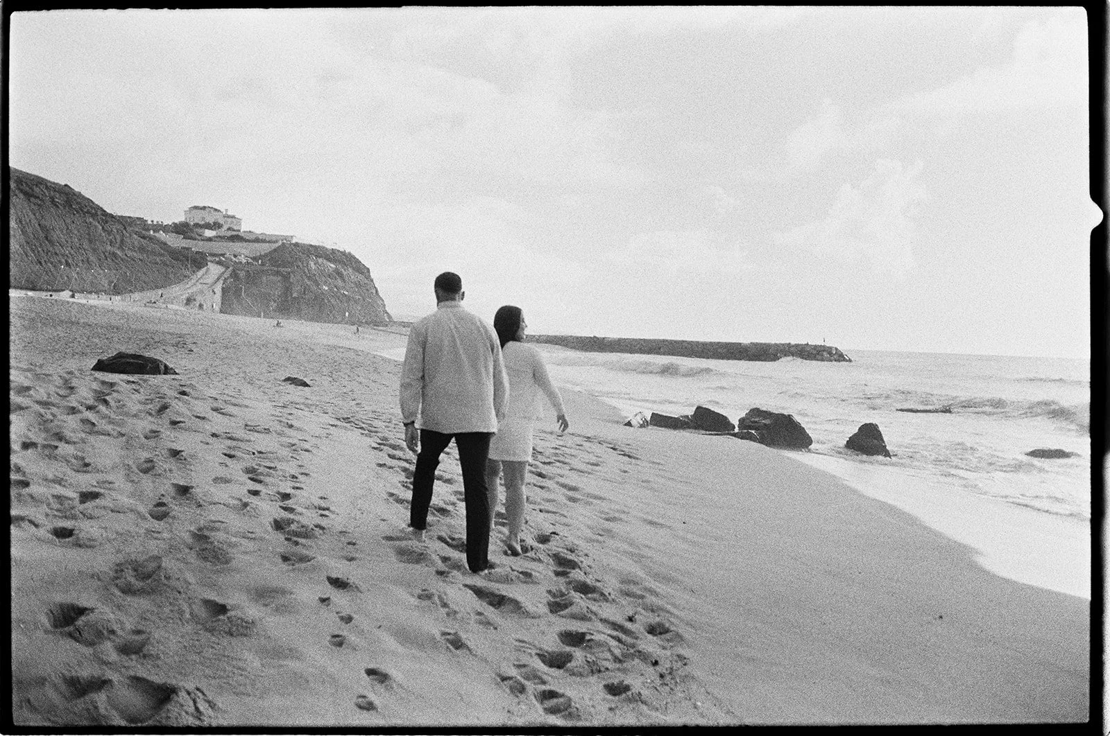 Couple walking together on a Algarve sandy beach in black and white film.